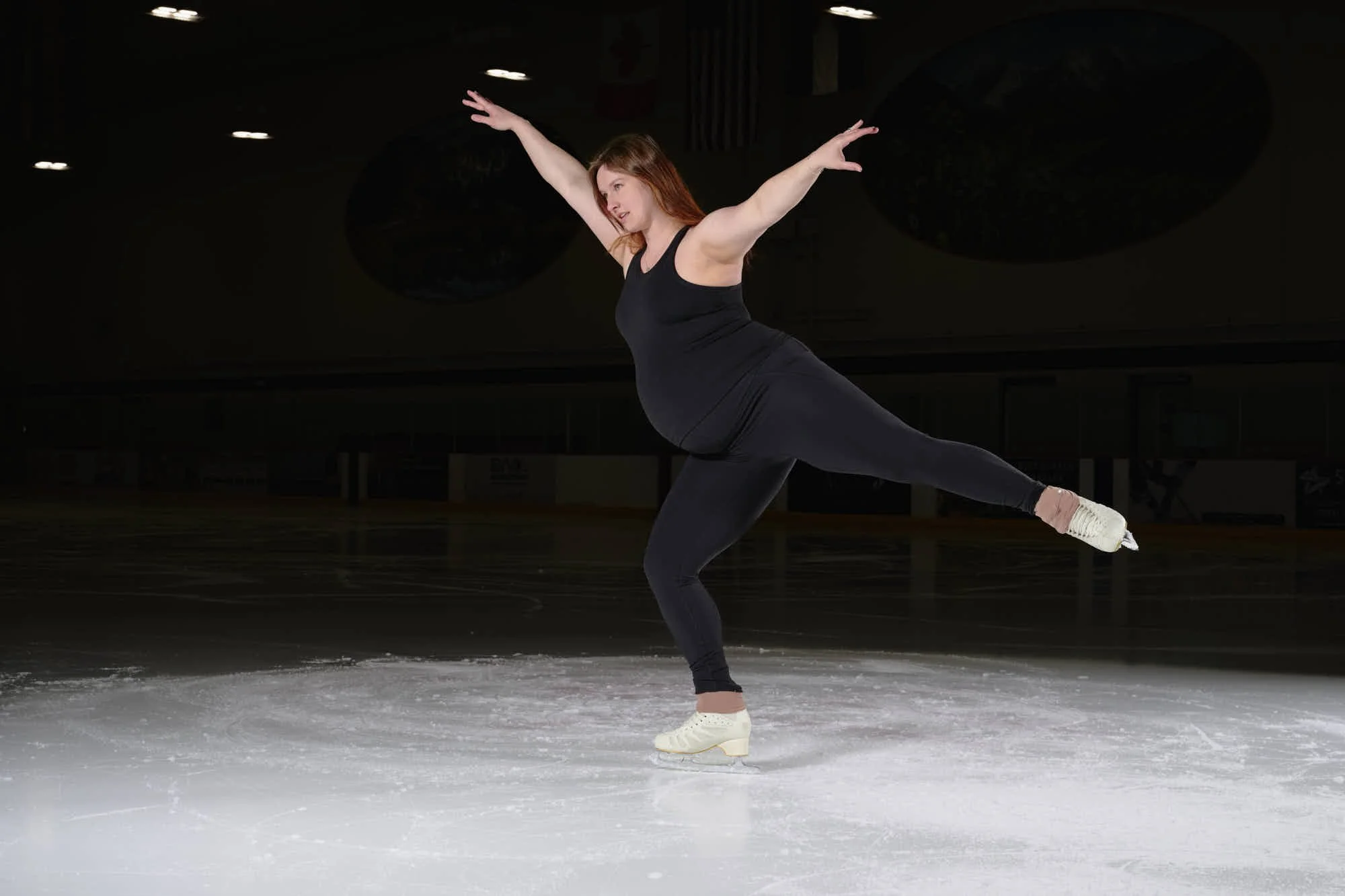 Long spiral down the rink with arms opened wide, navy skating tights.