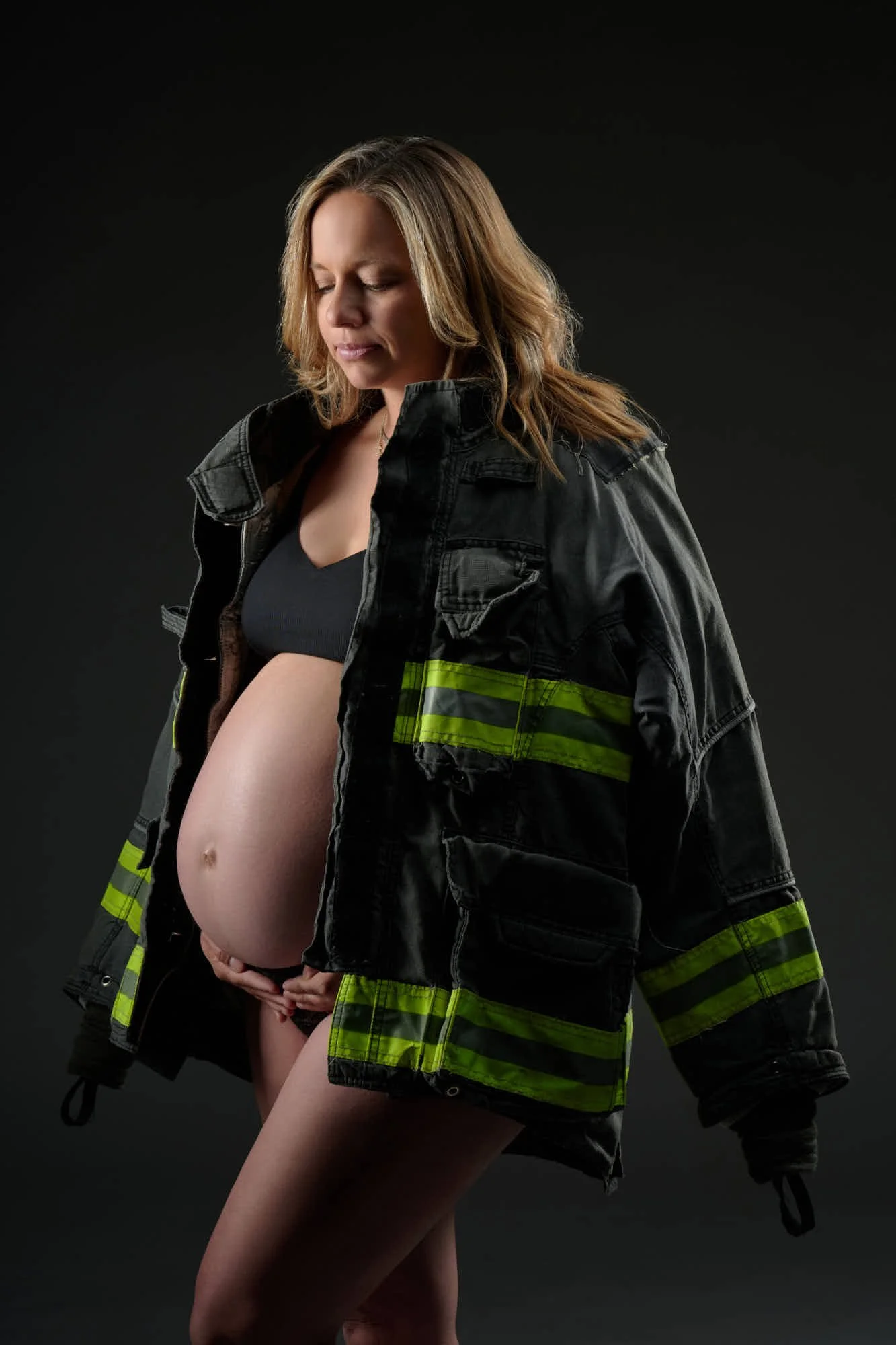 Firefighter turnout jacket over a bare baby bump, a personal touch in the Denver studio.