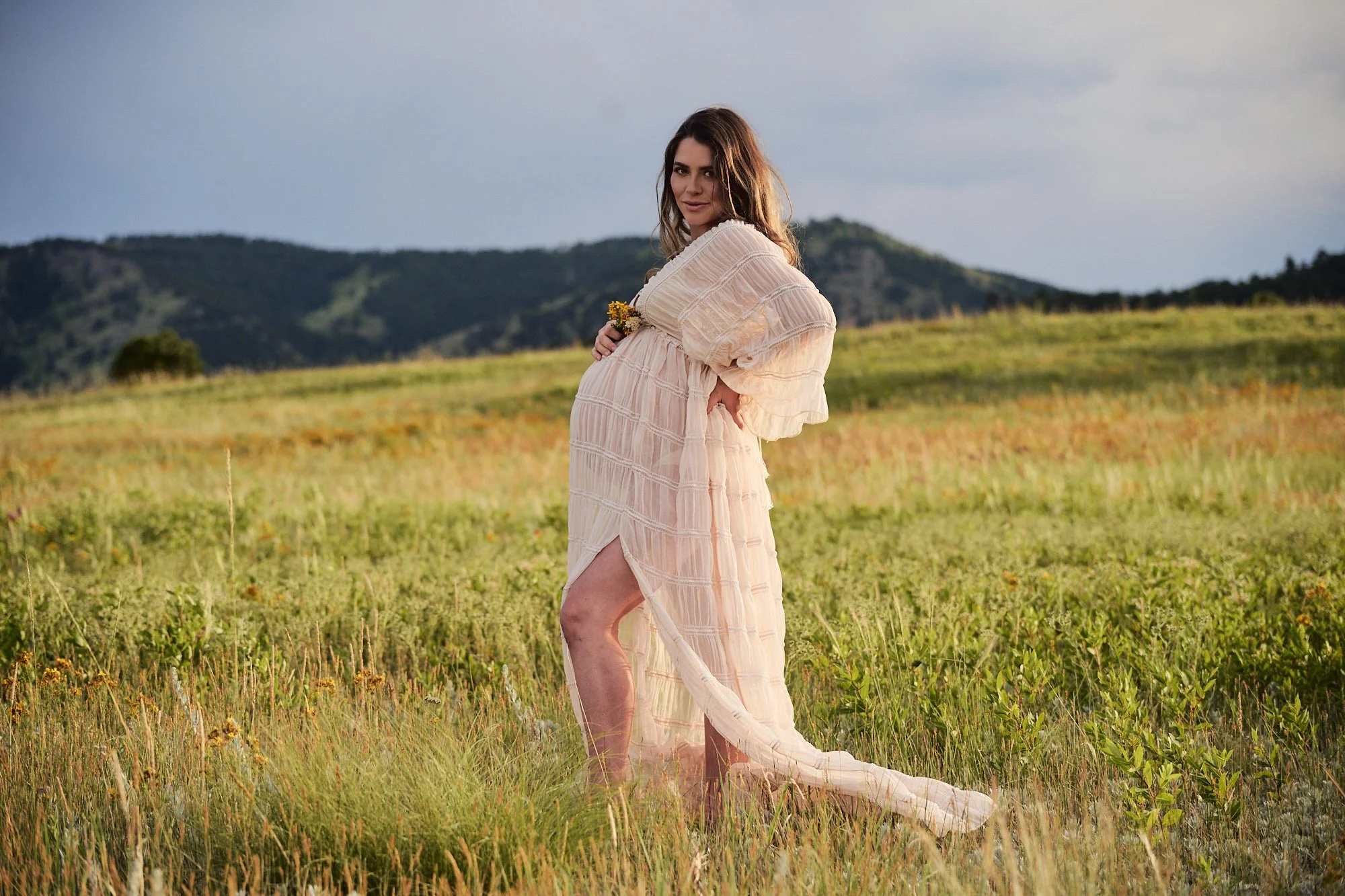 Textured cream robe mid-stride on a golden hillside during her outdoor maternity photoshoot.
