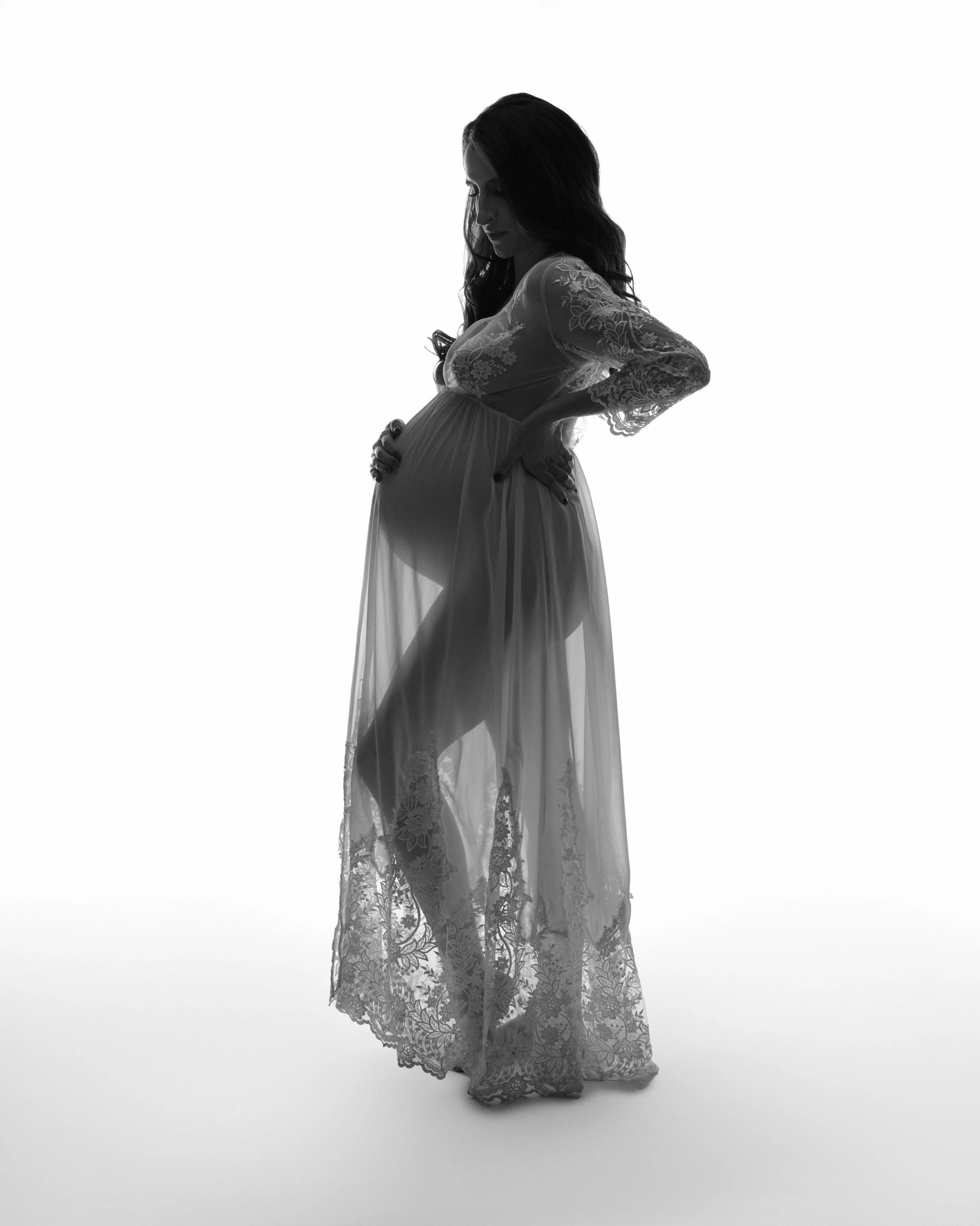 Black and white high-key frame, a sheer robe catching the light mid-motion.