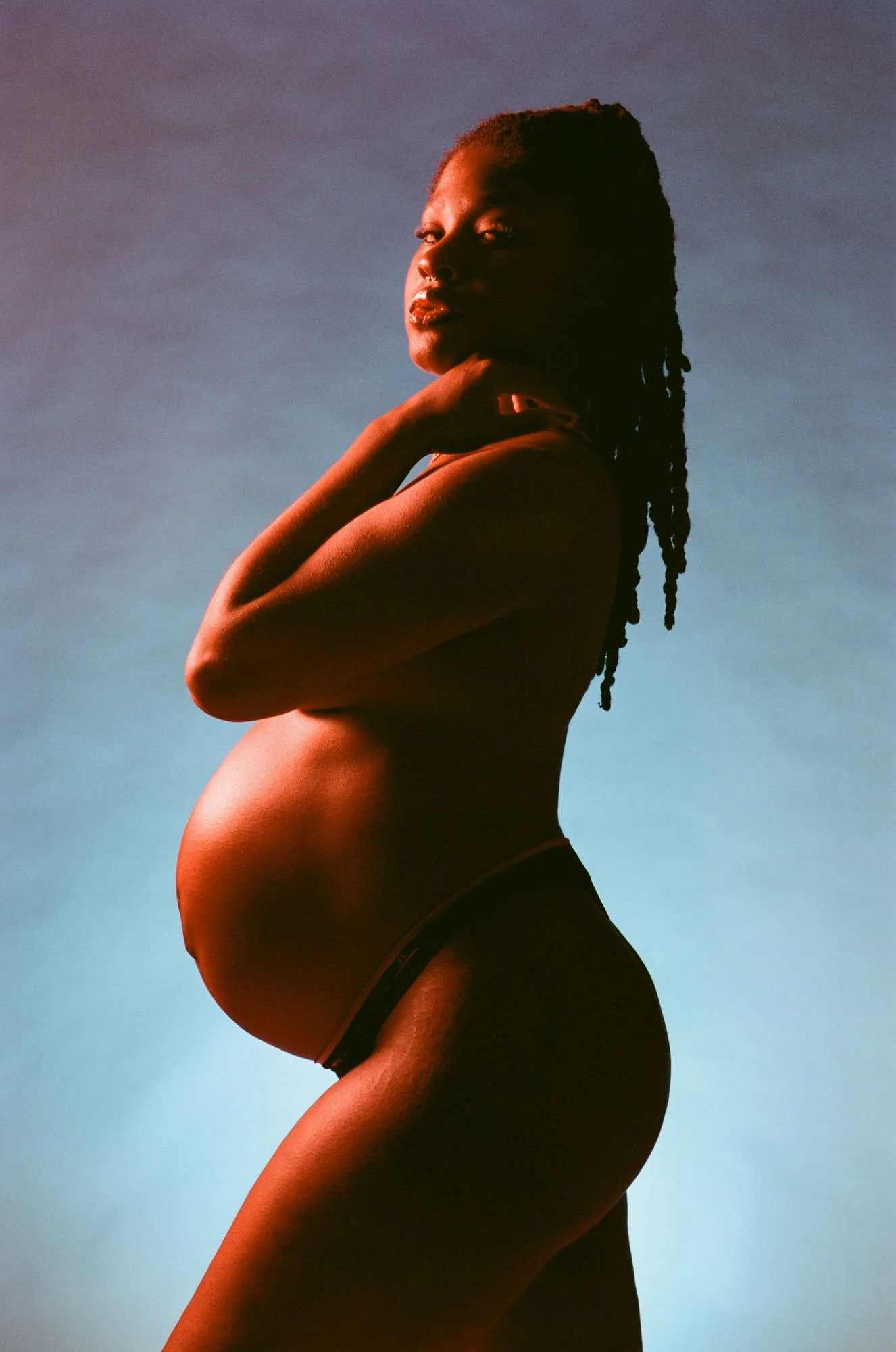Warm and cool gels crossing on bare skin, braids down her back, profile turned to the light.