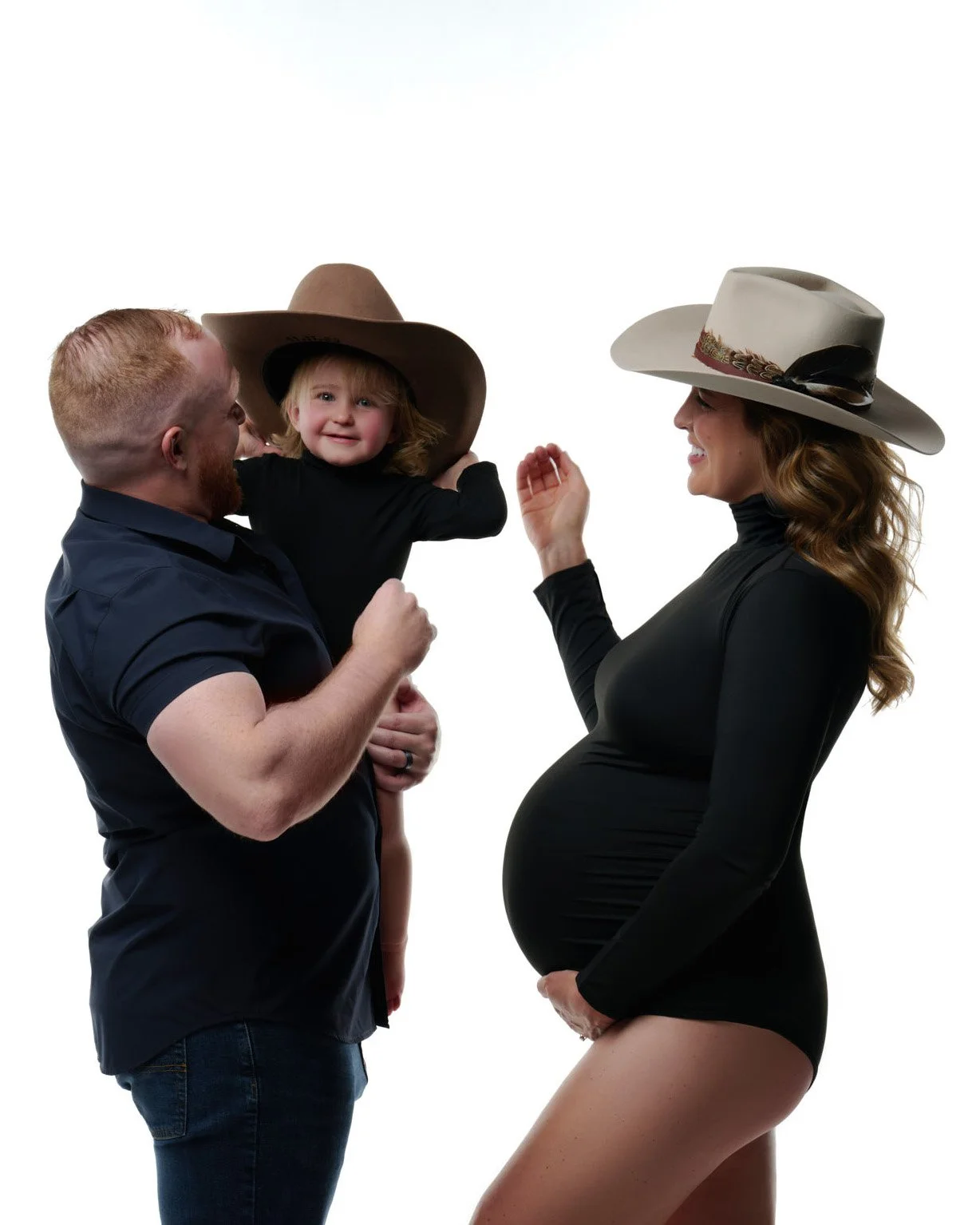 Family in cowboy hats laughing together during a studio maternity session by Ethan Herrold.