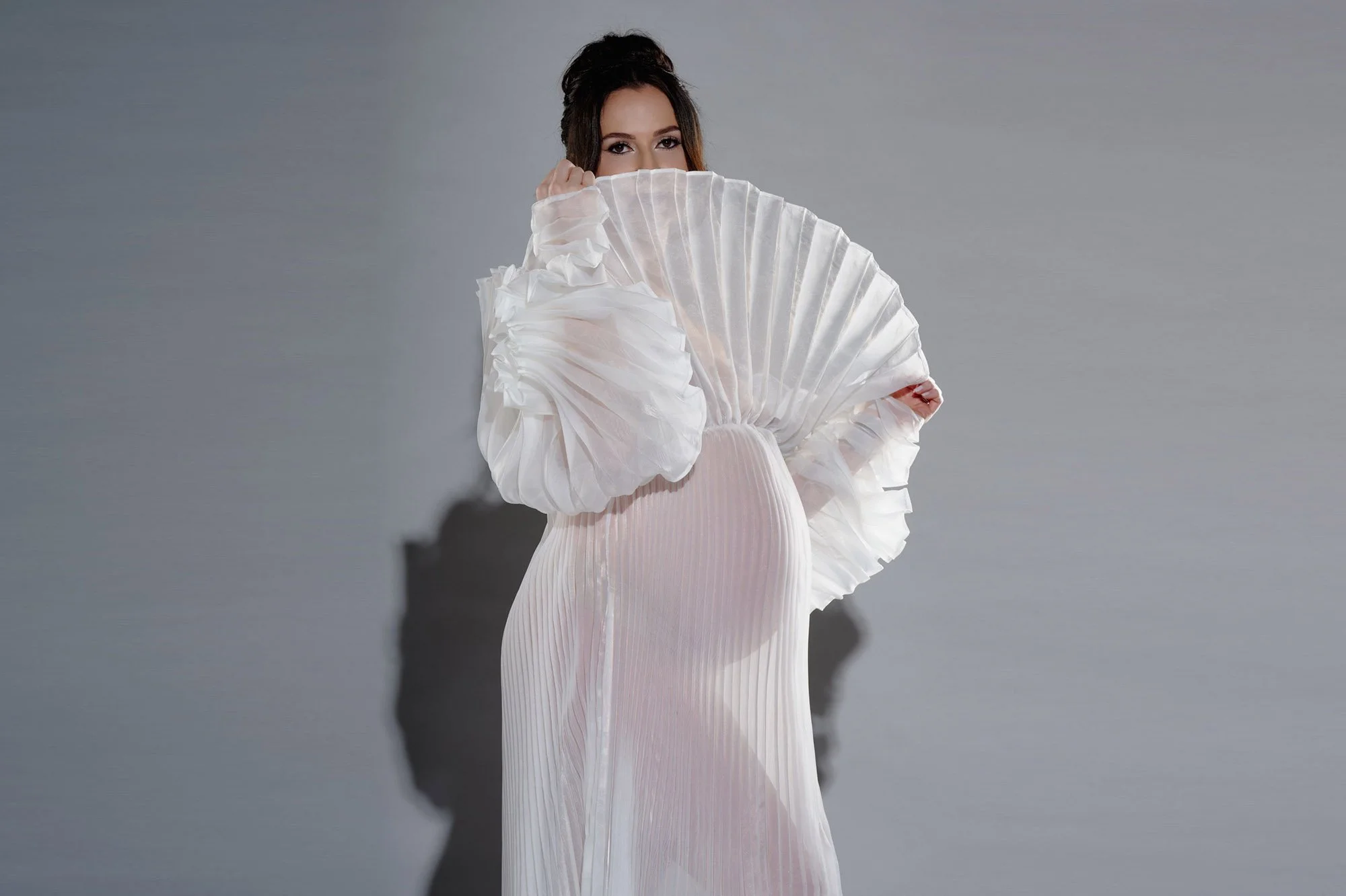 Sculptural pleated fan dress in the maternity photoshoot studio, Denver, Colorado.