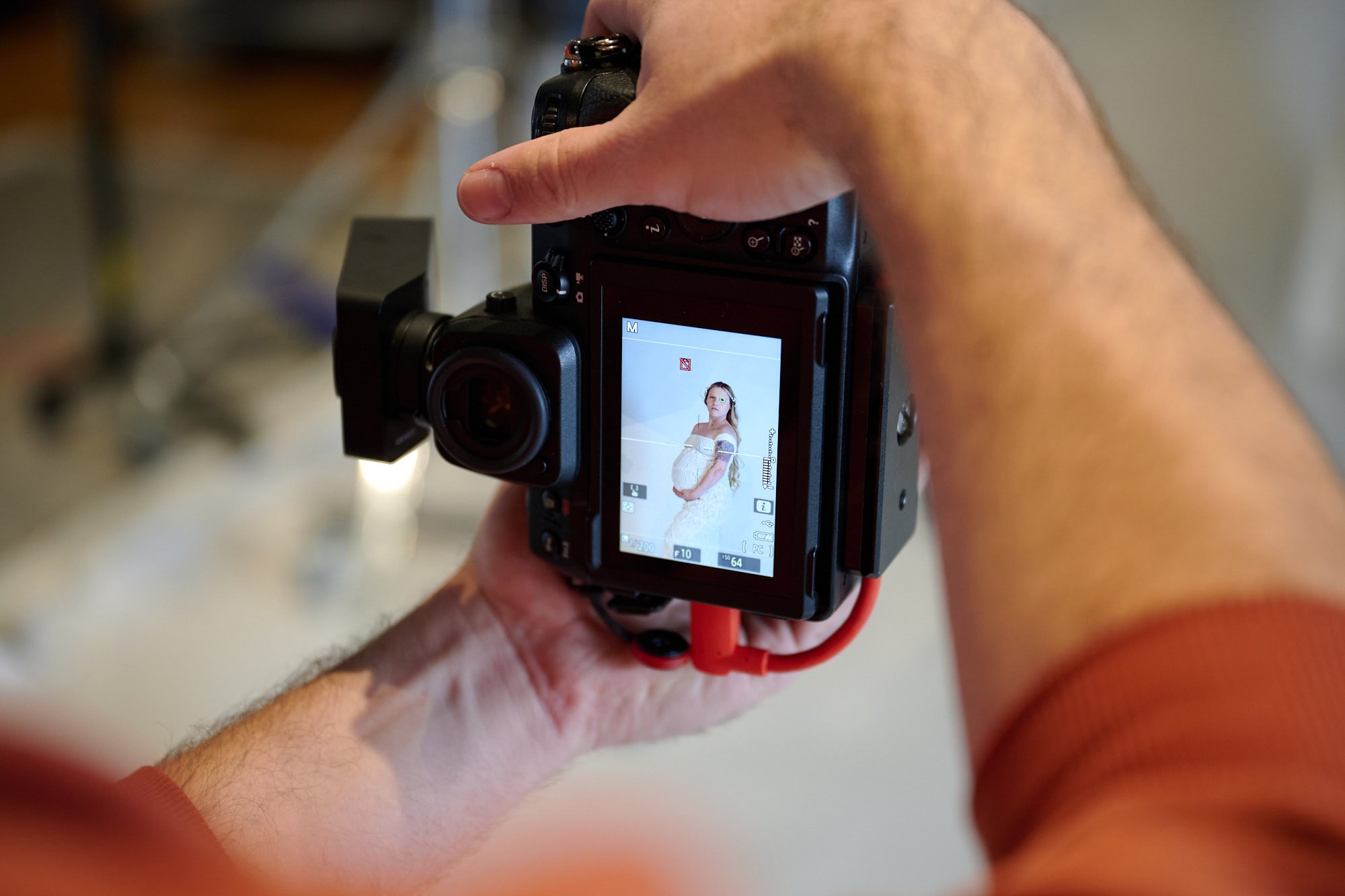 Camera in hand on the shooting floor, a portrait framed on the rear screen.