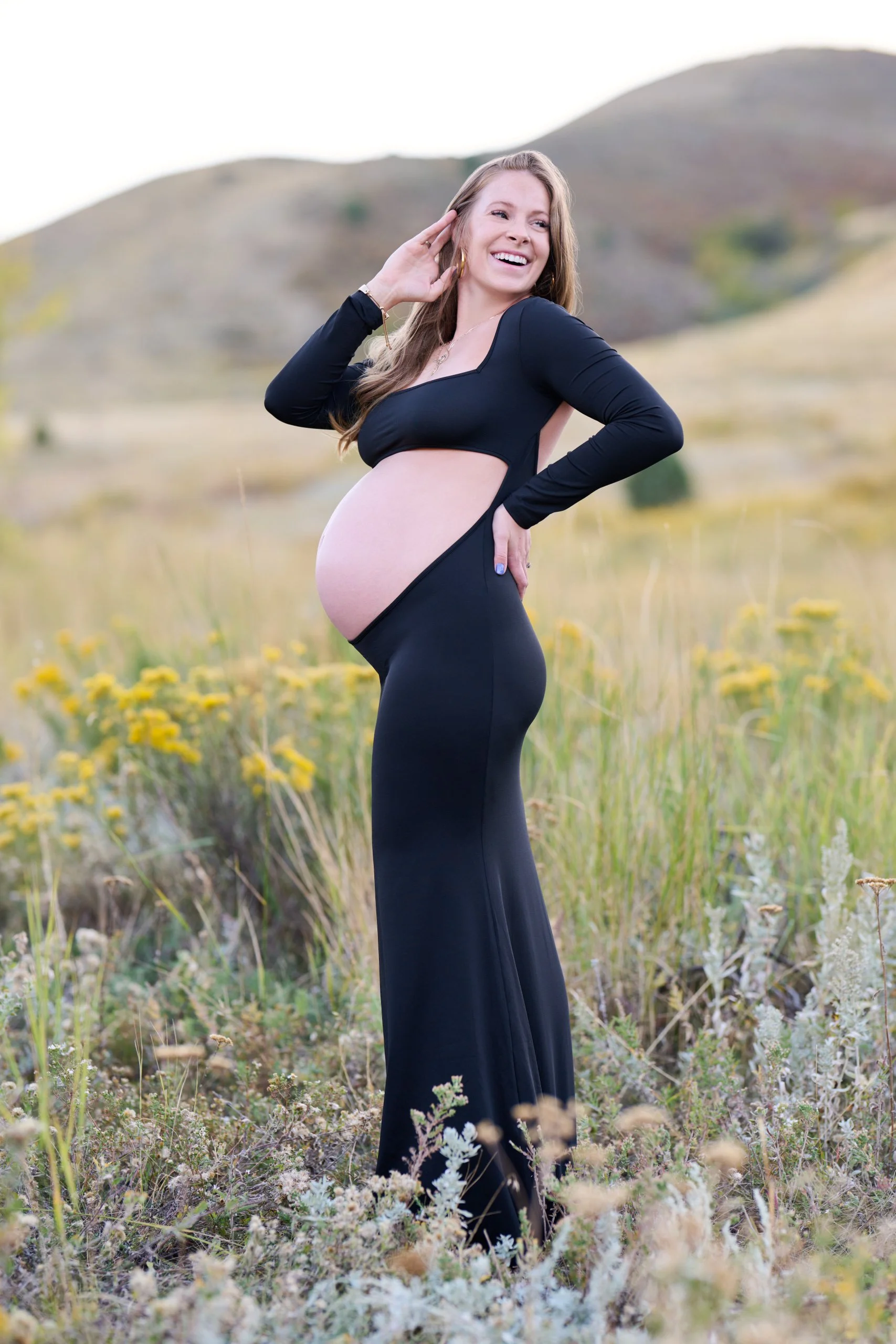 Black gown in a hillside of golden rabbitbrush, playfully shielding her eyes from the sun.