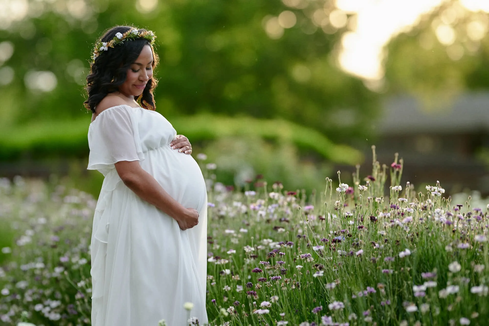 White flutter sleeve dress and a floral crown among wildflowers in a green summer garden.