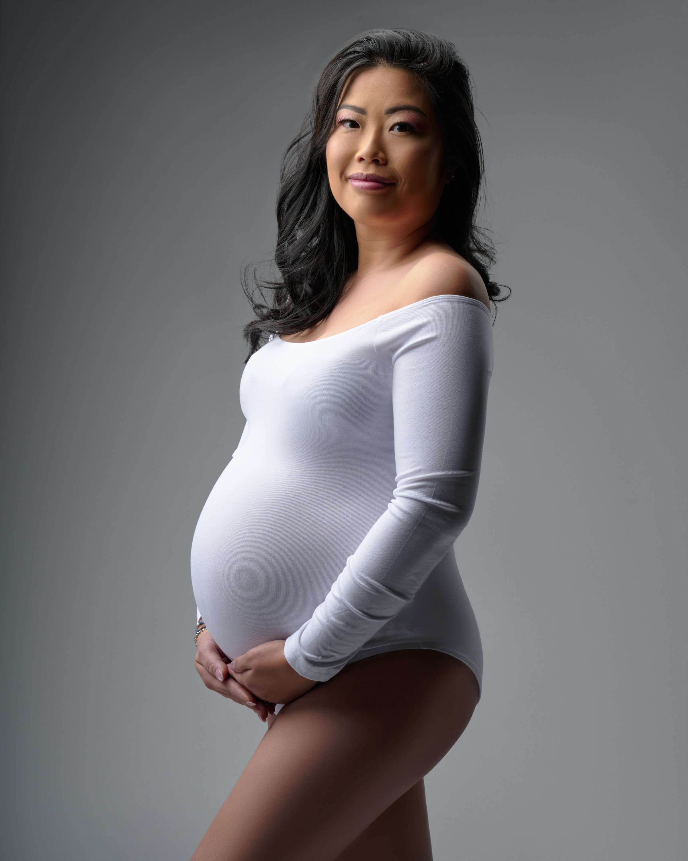 Simple maternity portrait in white bodysuit at Denver studio