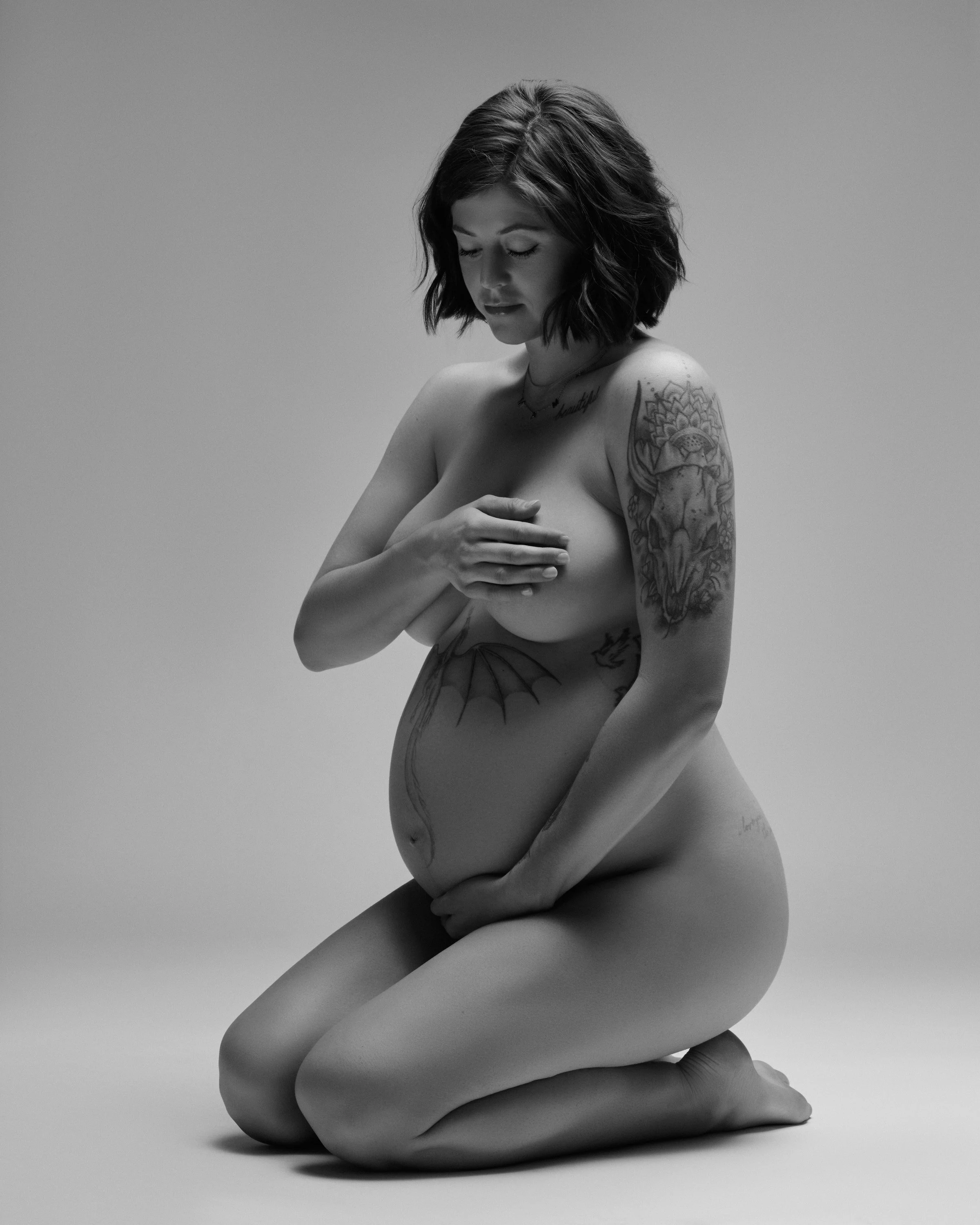 Black and white kneeling pose, soft fabric gathered at her waist.