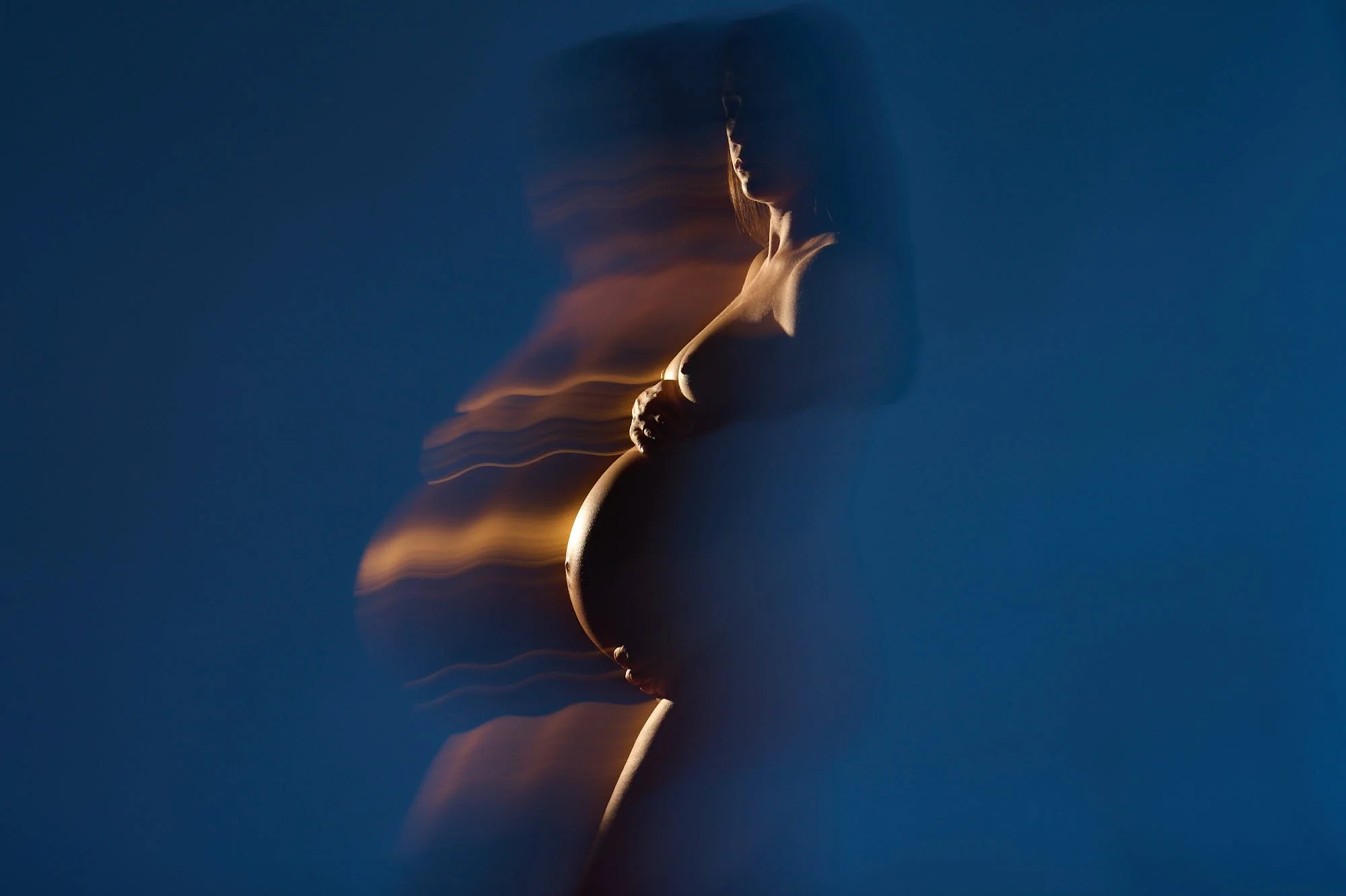 Golden light-painting streak tracing her silhouette against deep blue.