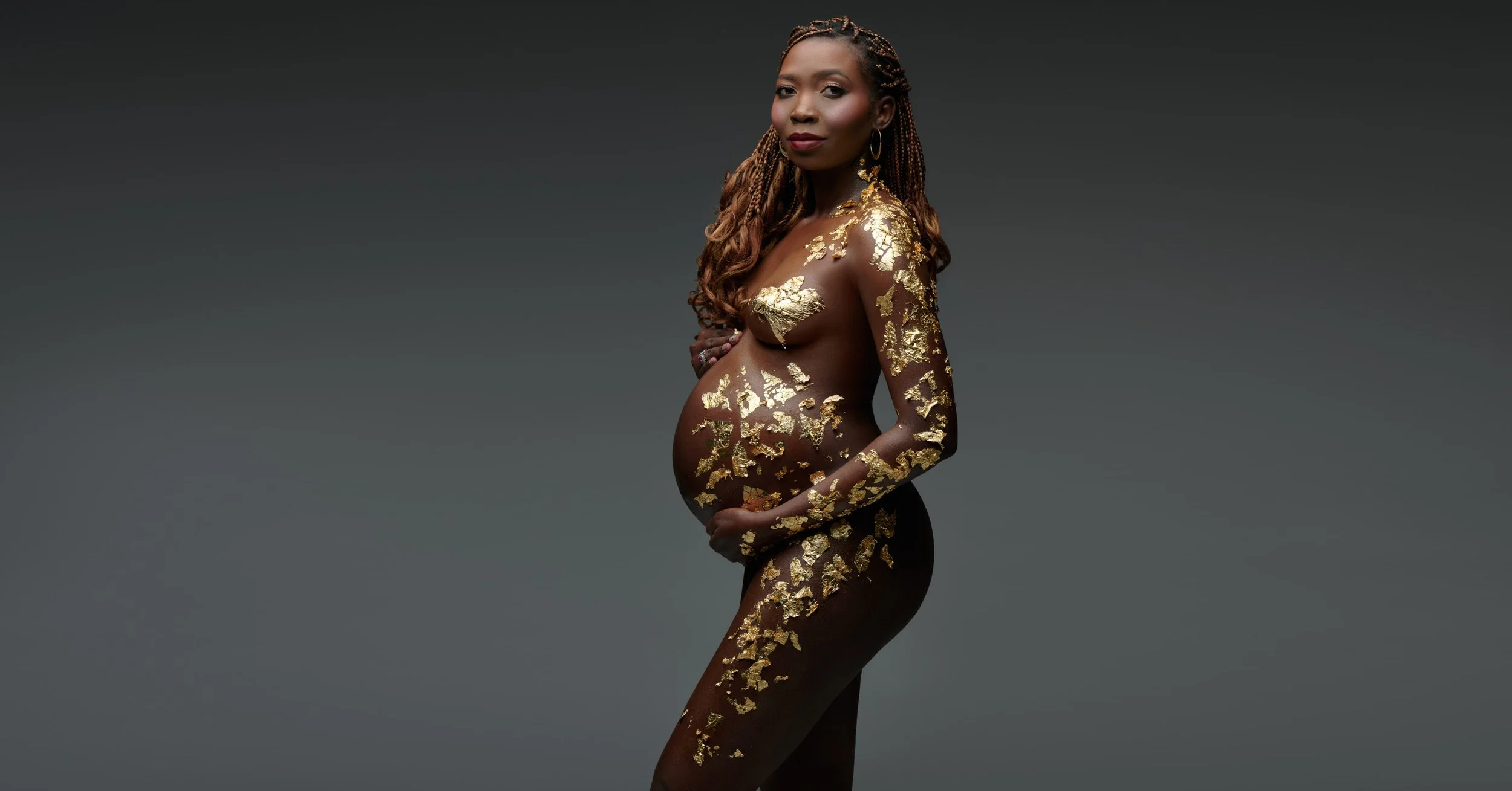 Gold sequin gown open around the bump, glowing against charcoal grey.