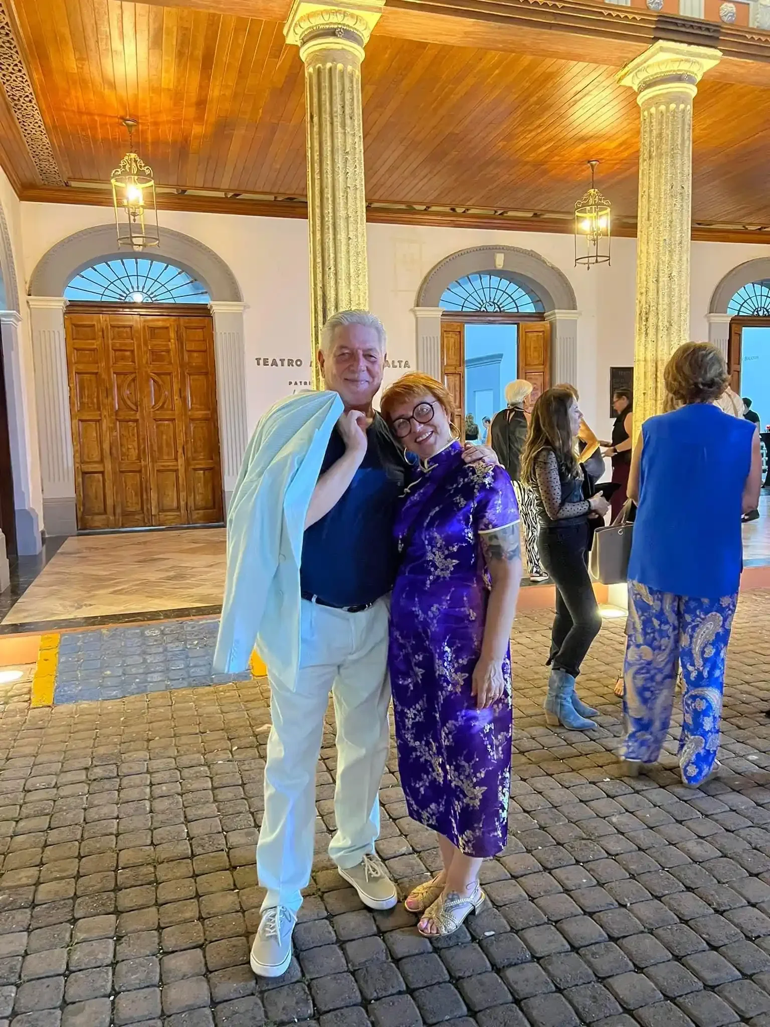 Inga and Randy outside the Teatro Ángela Peralta in Mazatlán before a performance of Verdi's Rigoletto, the gilded columns of the portico lit behind them.