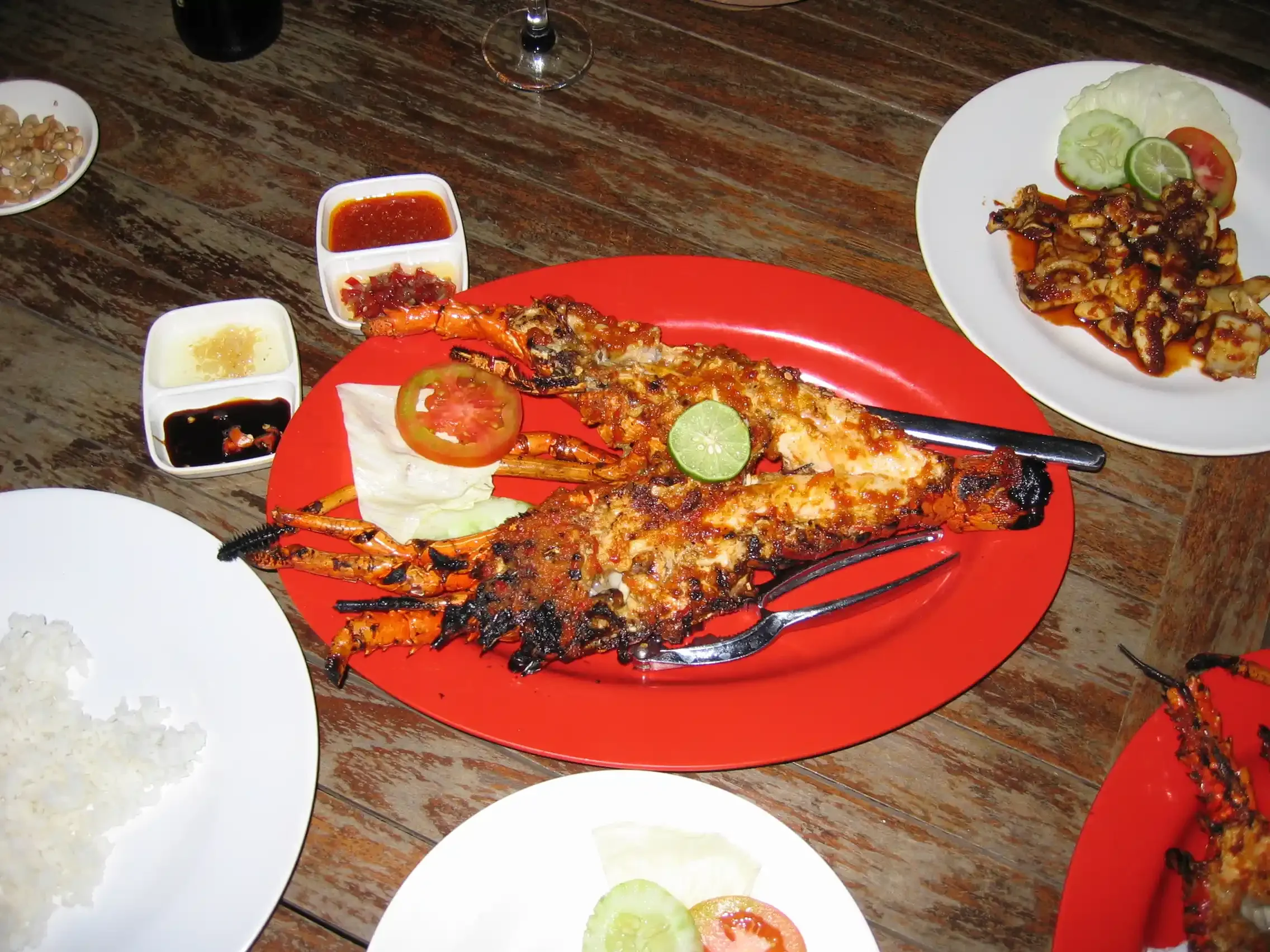 A grilled seafood dinner on a red plate at a restaurant in Lovina, Bali