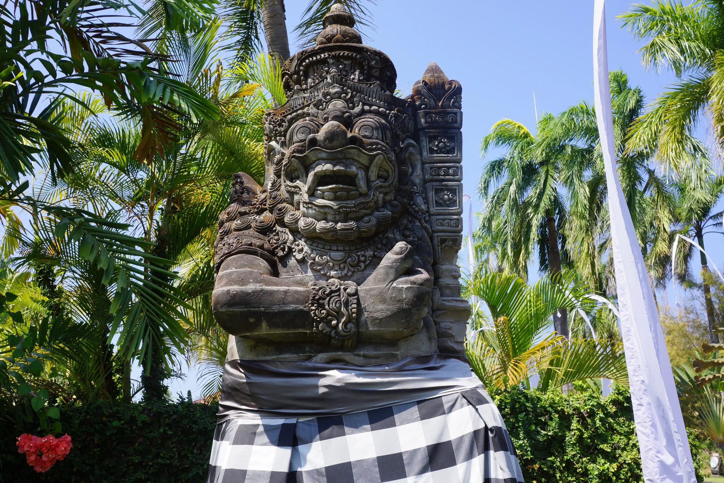 A stone temple guardian statue in black-and-white poleng cloth in north Bali