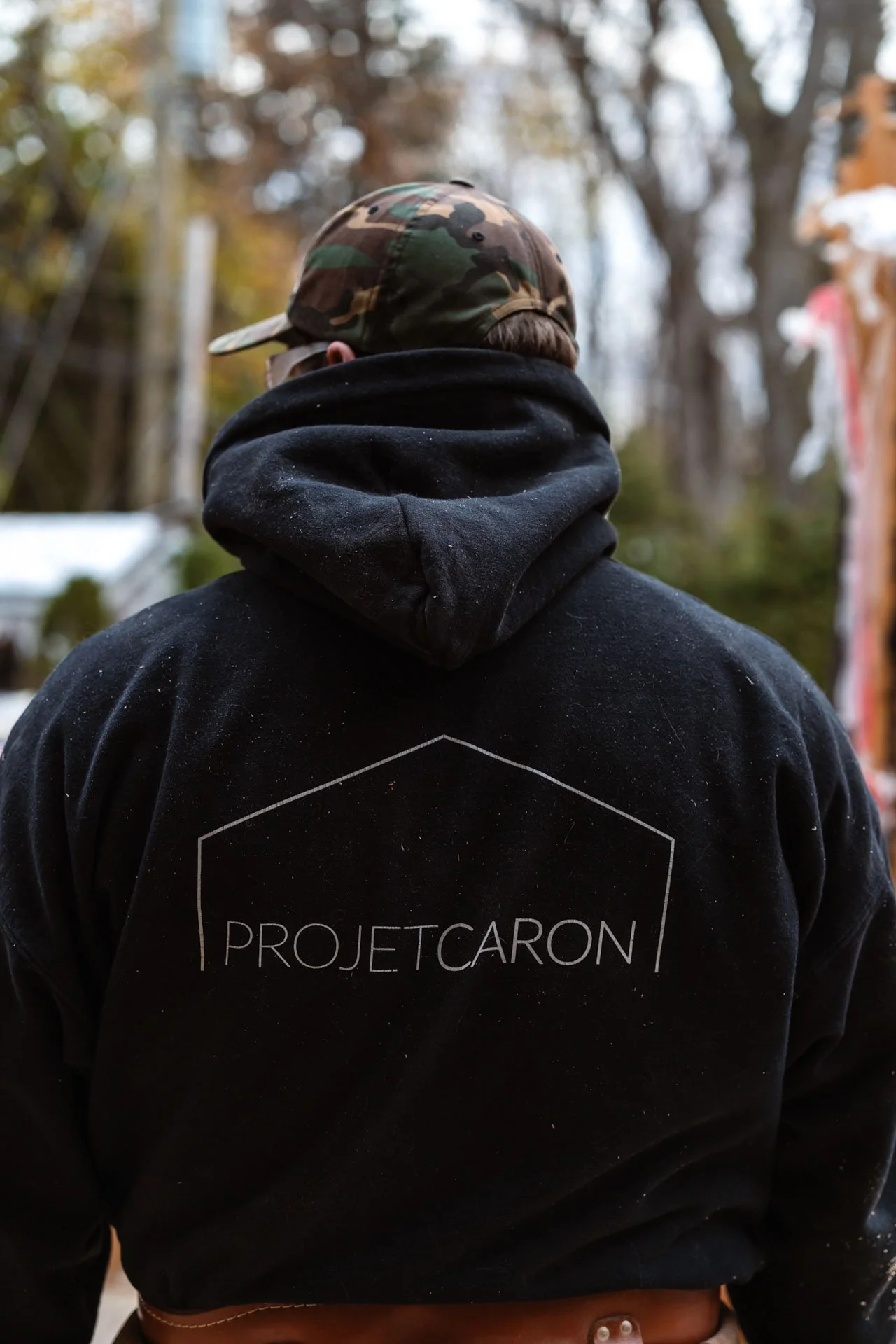 Dos d'un travailleur portant le logo Projet Caron, entrepreneur général