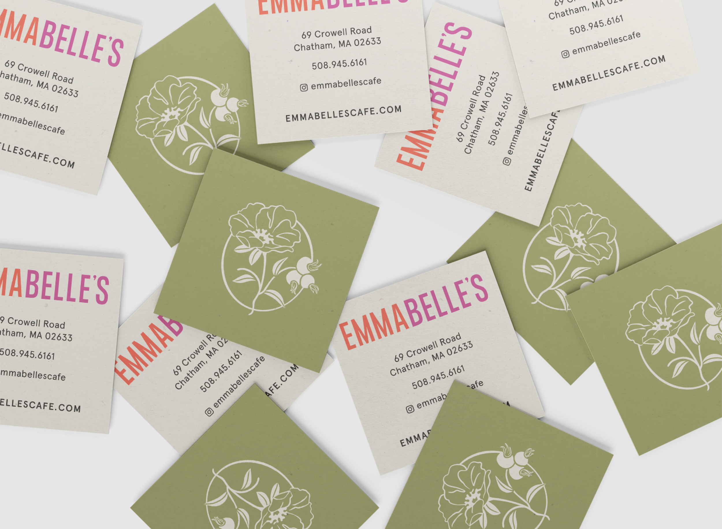 Business cards for Emma Belle's café. The cards have a design with a green background featuring white floral drawings, and the text is in pink, purple, black, and red.