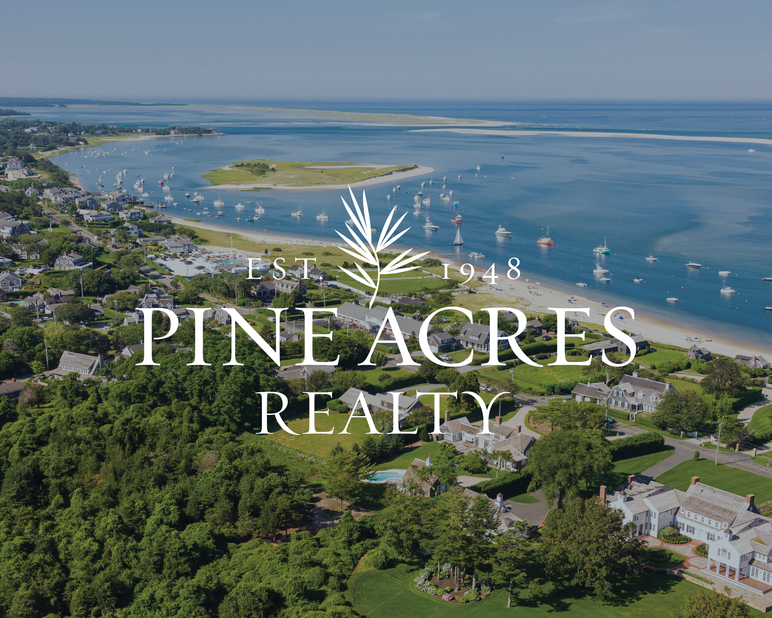 An aerial view of a coastal town with houses, green trees, and boats in the water, featuring a logo for Pine Acres Realty established in 1948.