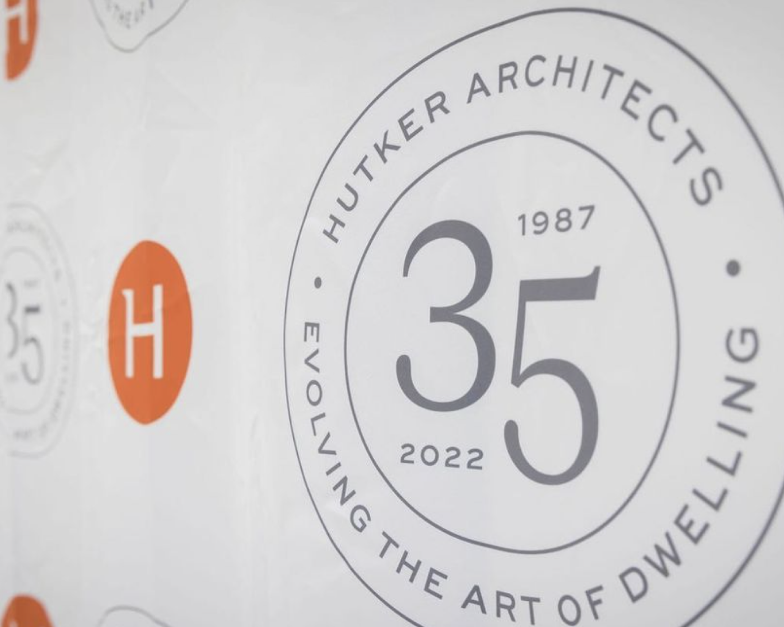Close-up of a circular design emphasizing the text 'HUTKER ARCHITECT', 'THE ART OF DESIGN', and the year '1987', with a small orange circle on the left side.