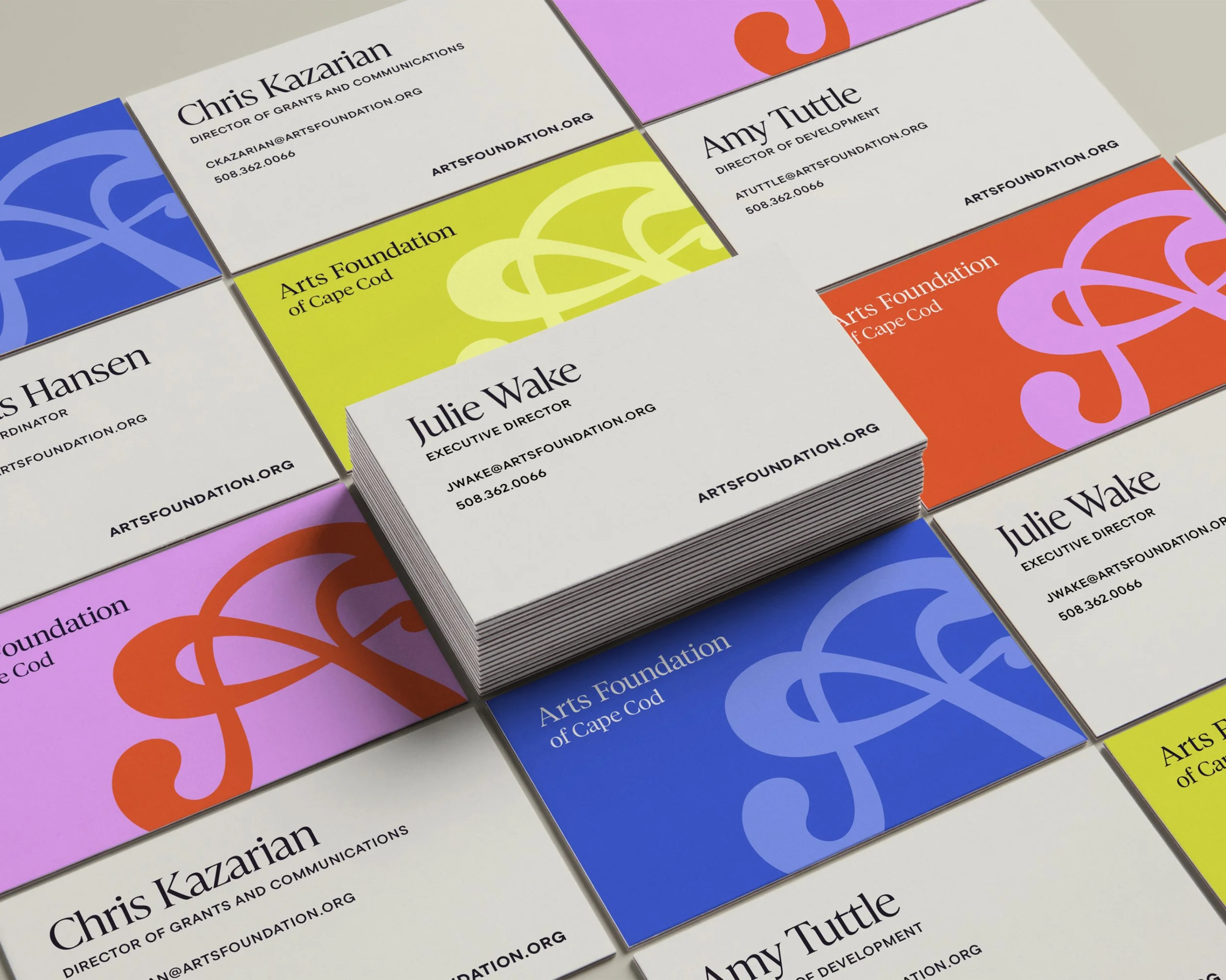 Stacked business cards for the Arts Foundation of Cape Cod featuring names, titles, email addresses, phone numbers, and colorful abstract logos in blue, yellow, purple, and orange.