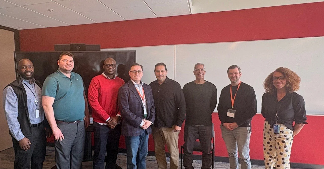 Line of professionals posing for picture in a conference room