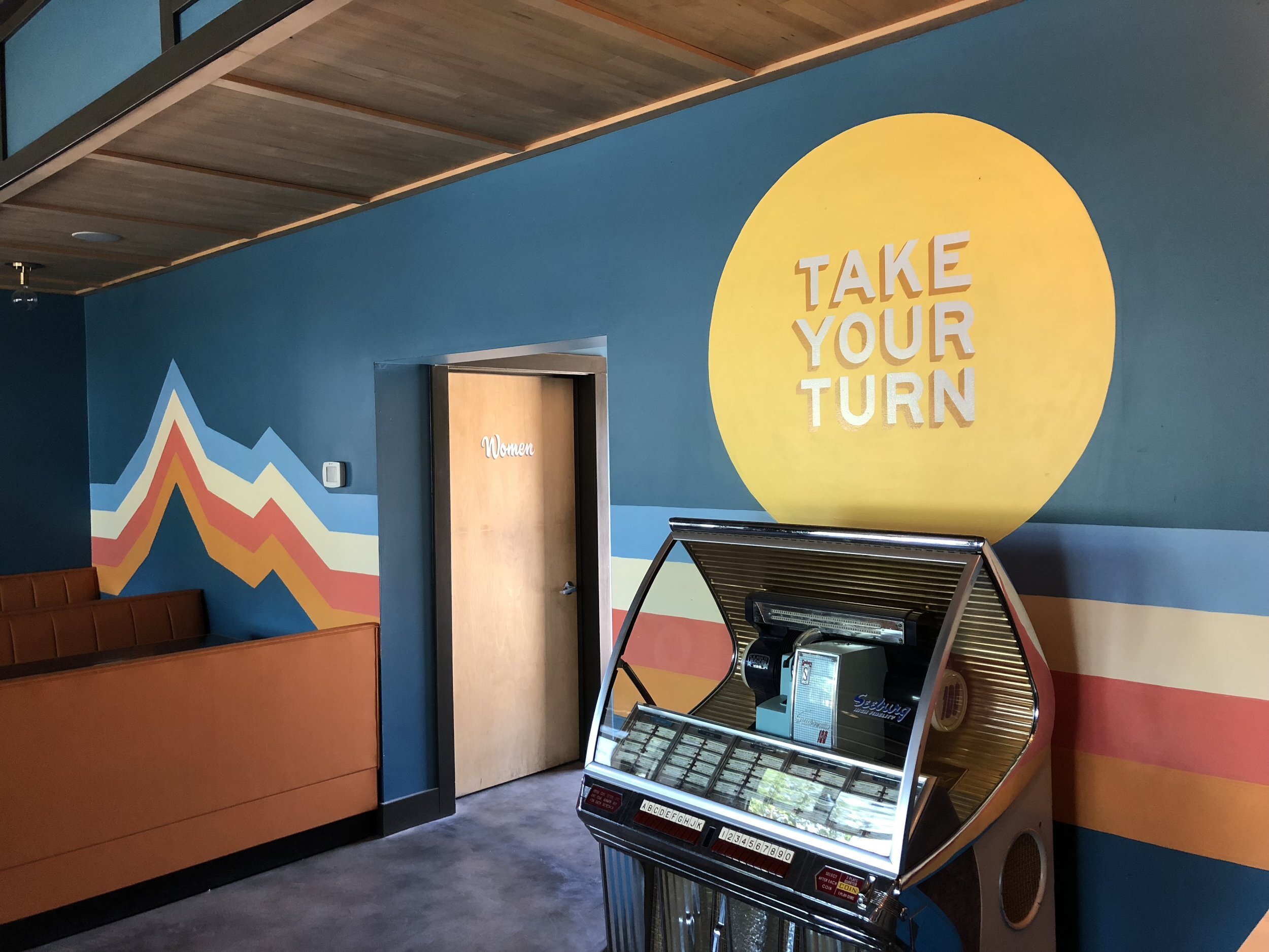 interior business mural reading "take your turn" hand painted by mural artist andrew manning