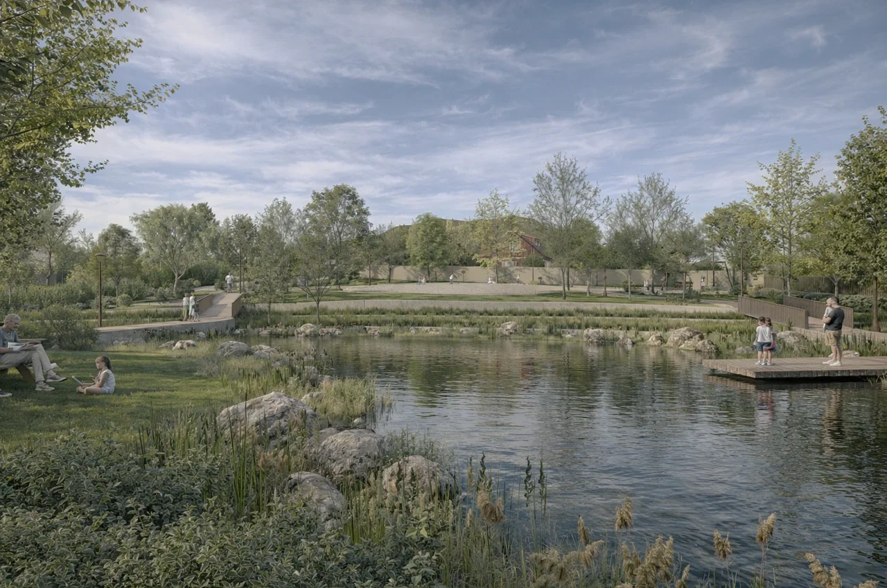 Un parque con un estanque en el centro, rodeado de árboles y áreas verdes. Personas sentadas en bancos y en la hierba, niños en un muelle de madera y adultos paseando por senderos pavimentados. El cielo está parcialmente nublado, creando un ambiente tranquilo y natural.
