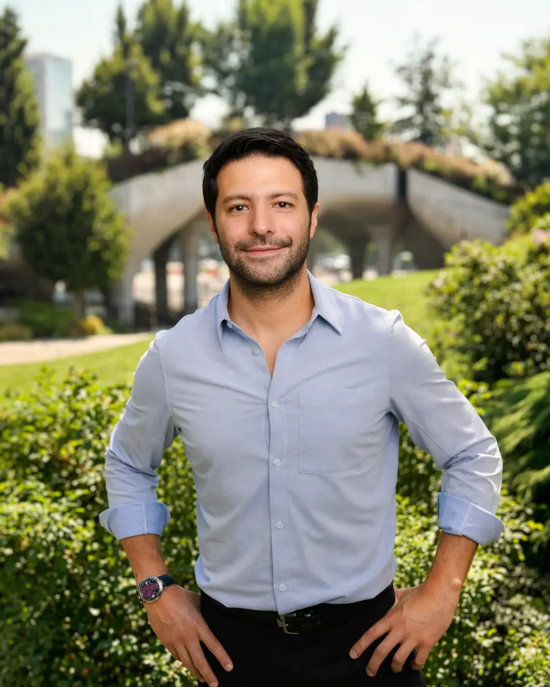 Hombre sonriendo con fondo de parque con vegetación y puente.