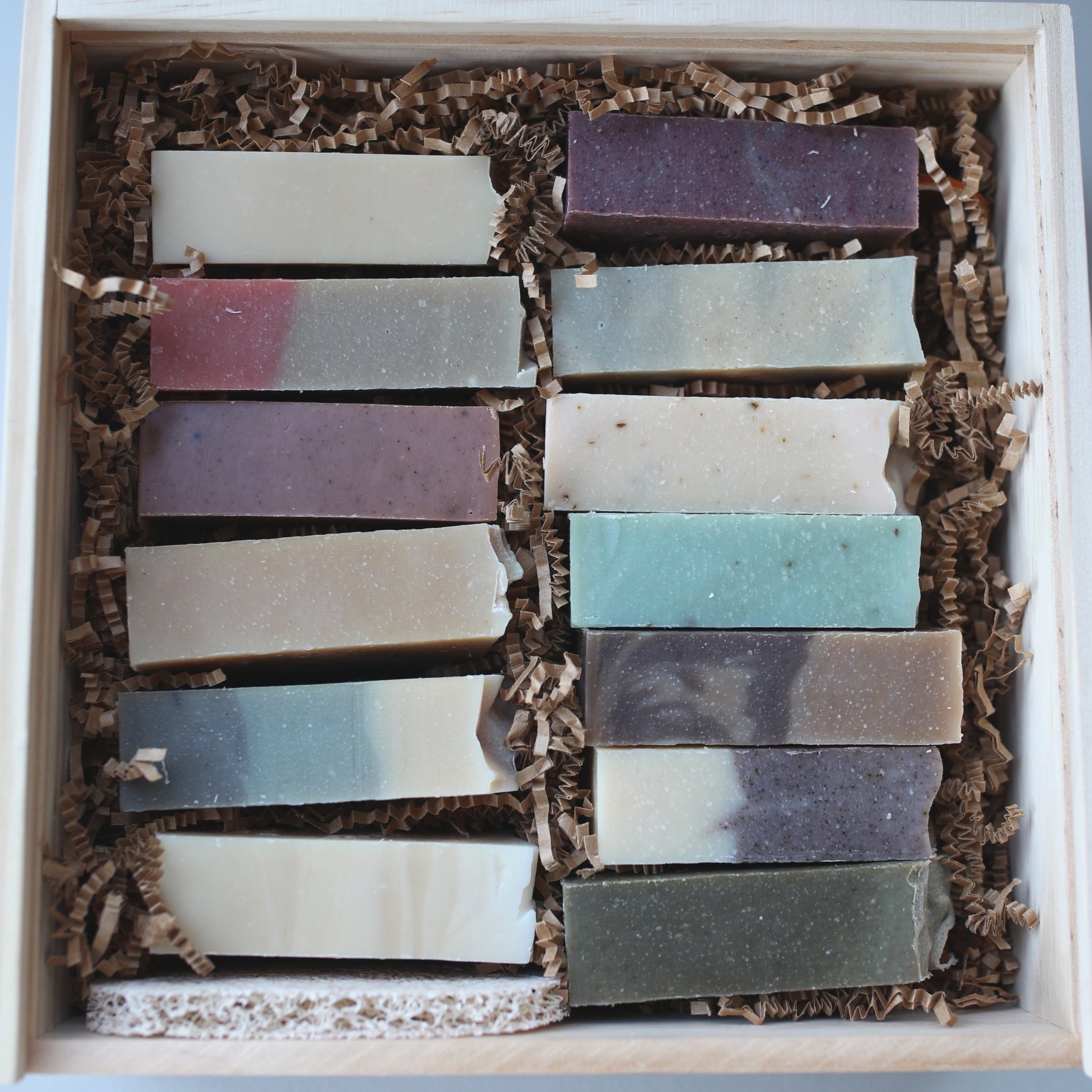 Large gift set with 13 natural goat milk soaps and soap saver, packaged in a pine wood box with dried botanicals.