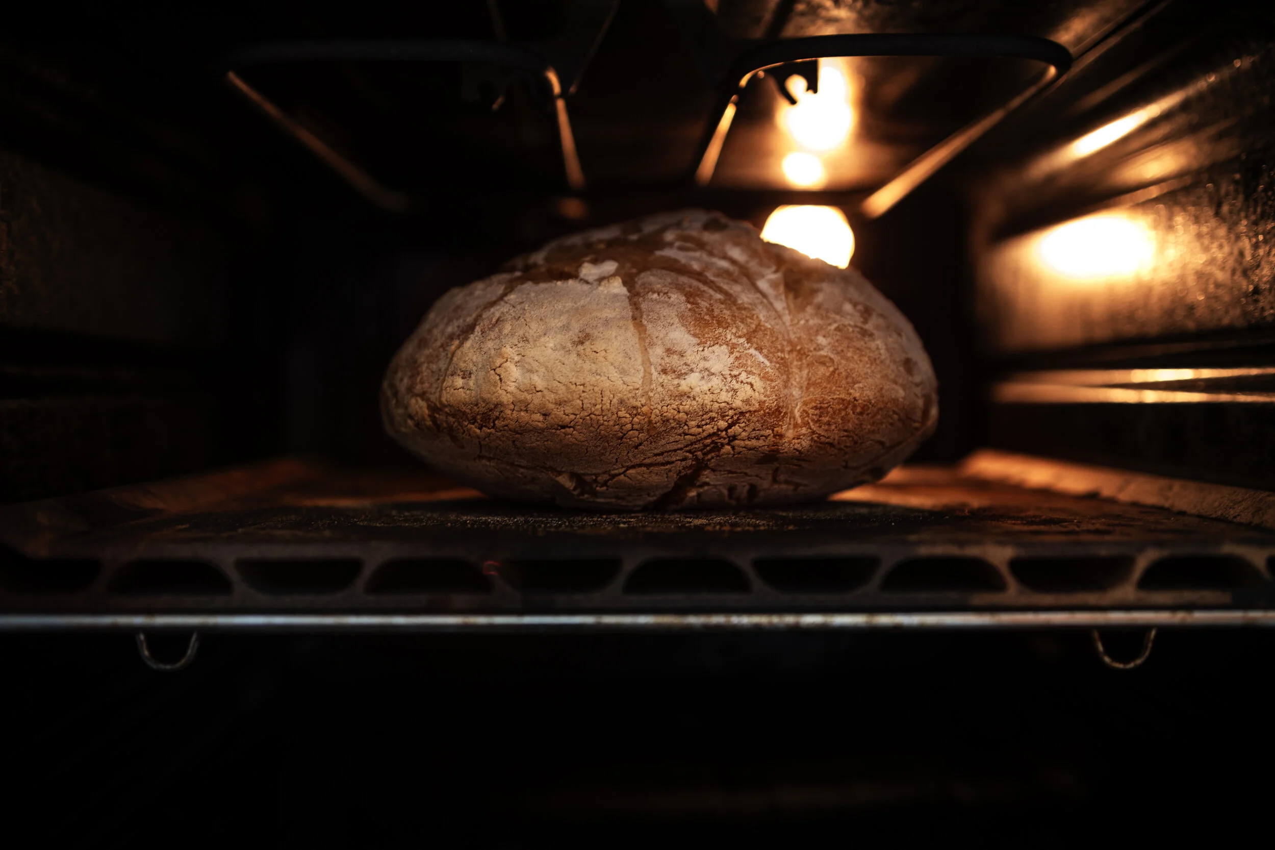 A loaf of bread baking inside an oven with warm lighting.