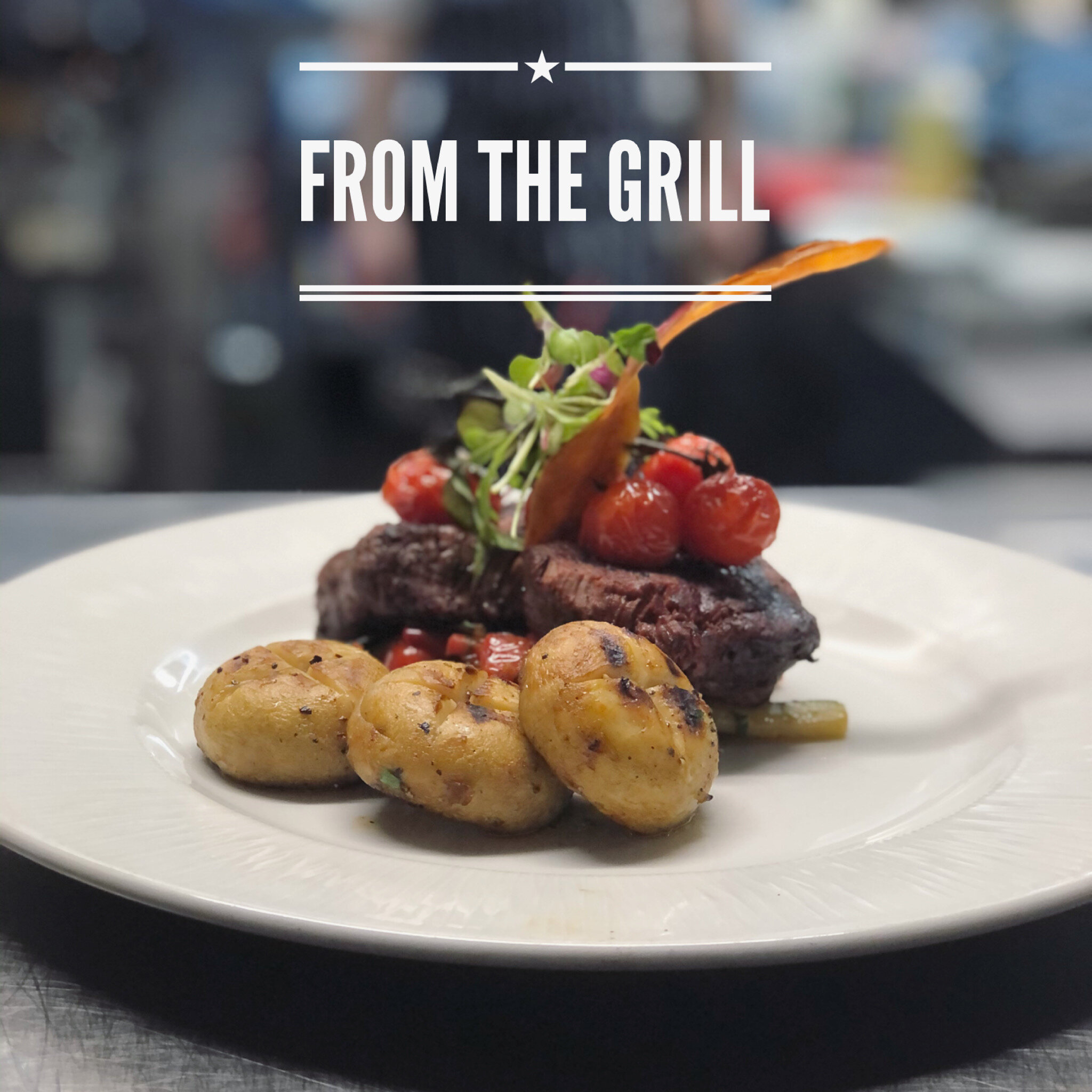 Plate of grilled meat topped with cherry tomatoes and garnished with greens, served with roasted potatoes on a white plate.