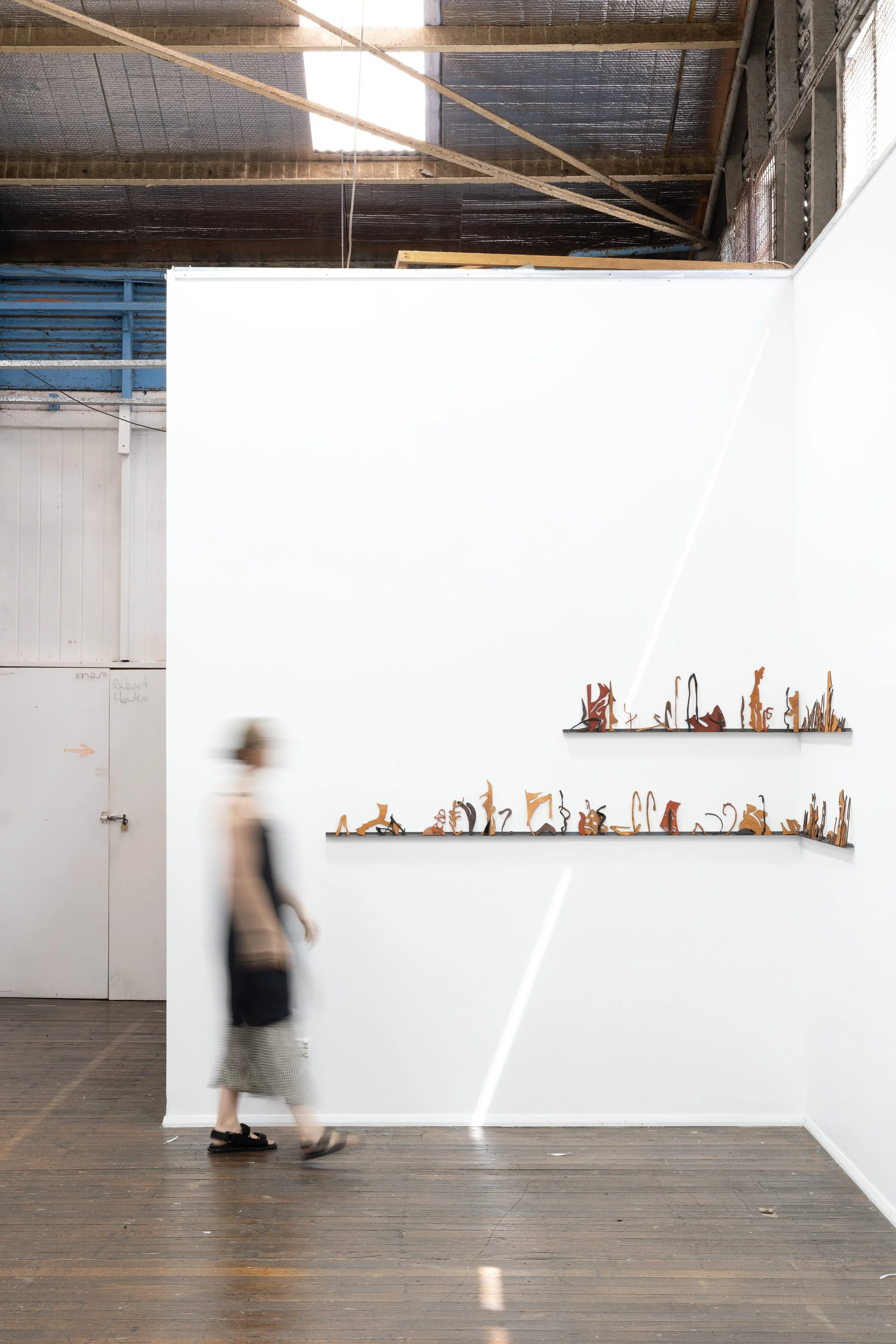 Tia Madden, 'Misreading Misreading,' installation view, Upspace Gallery, 2025. Stained and black tinted resin-coated plywood on steel shelf; 70 x 300cm. Photograph: Jessica Maurer