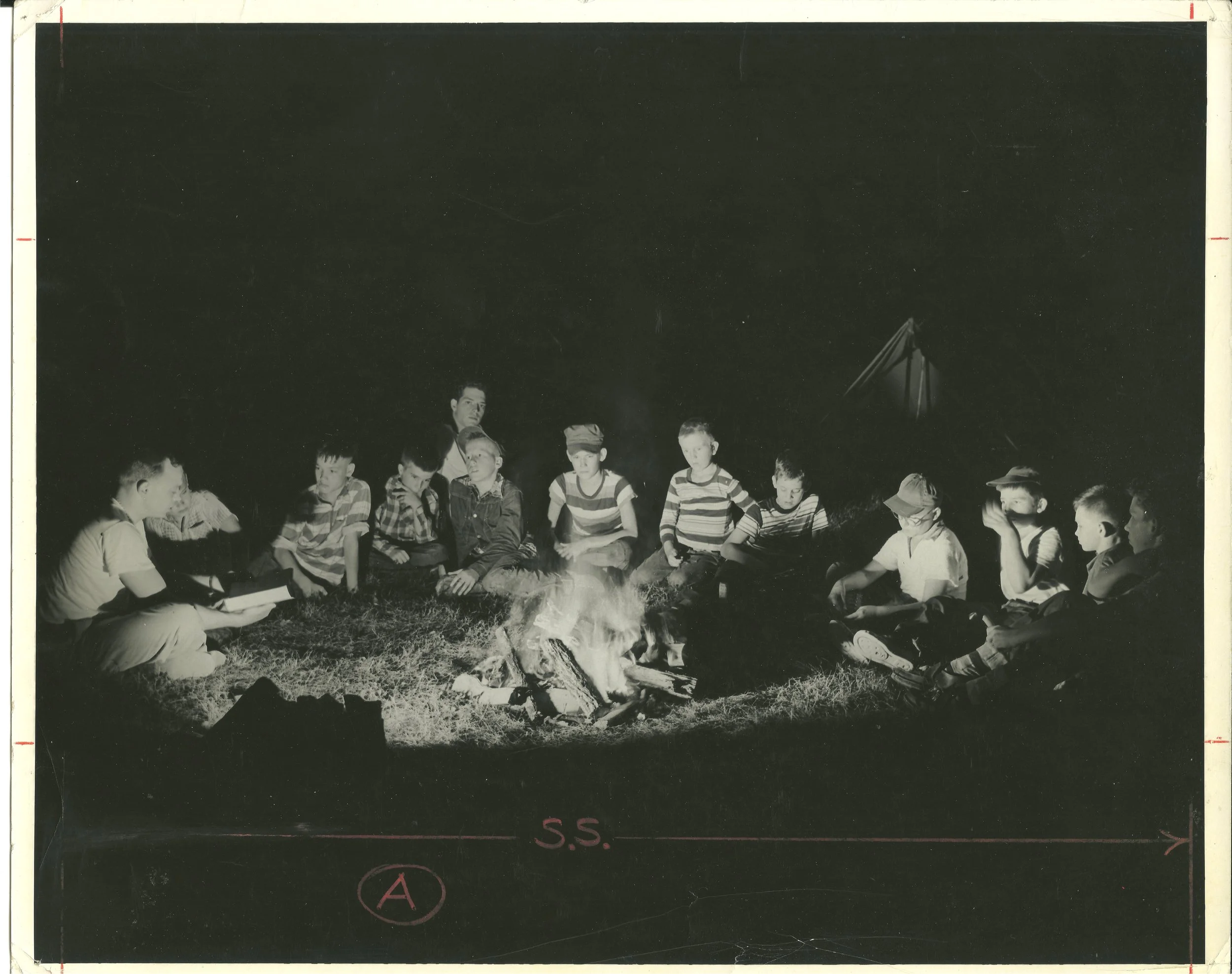 1940s - Campers sit around a campfire
