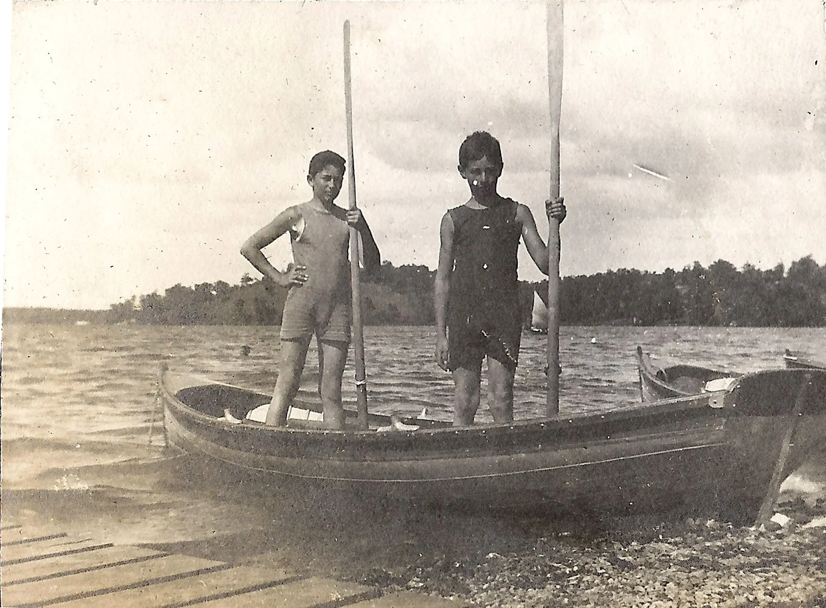 1900s - Two boys stand up in a canoe with their paddles