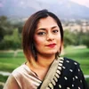 a Bangladeshi Muslim woman standing in front of trees and mountains.