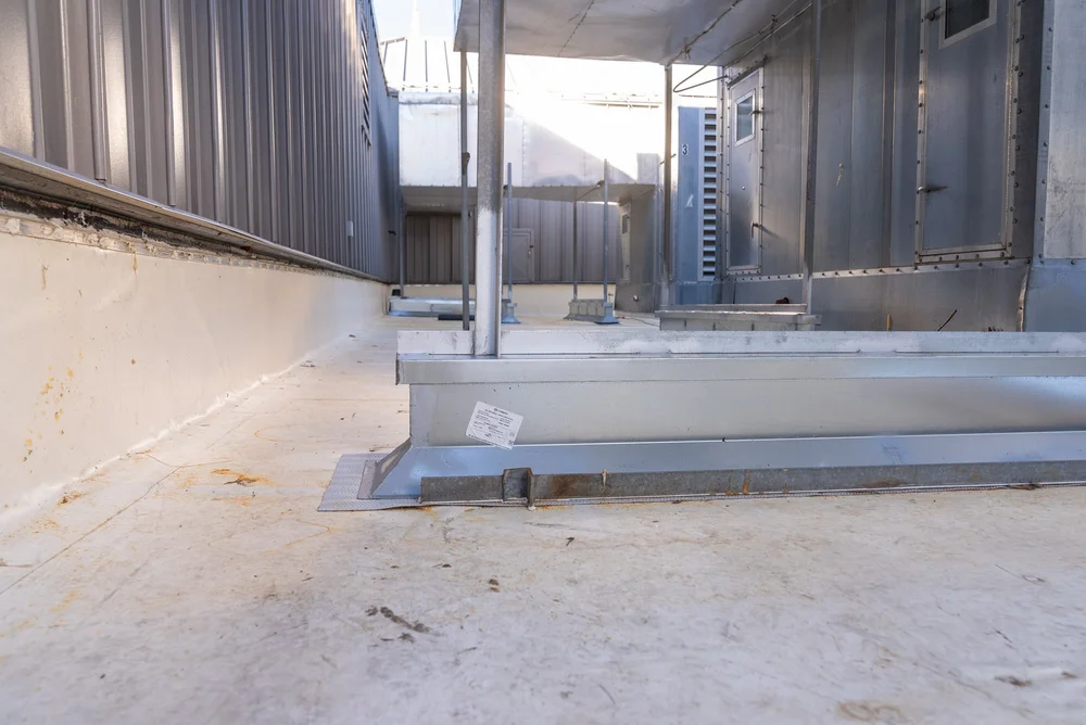 View of a rooftop with metal structures, vents, and a concrete surface, taken from a low angle.