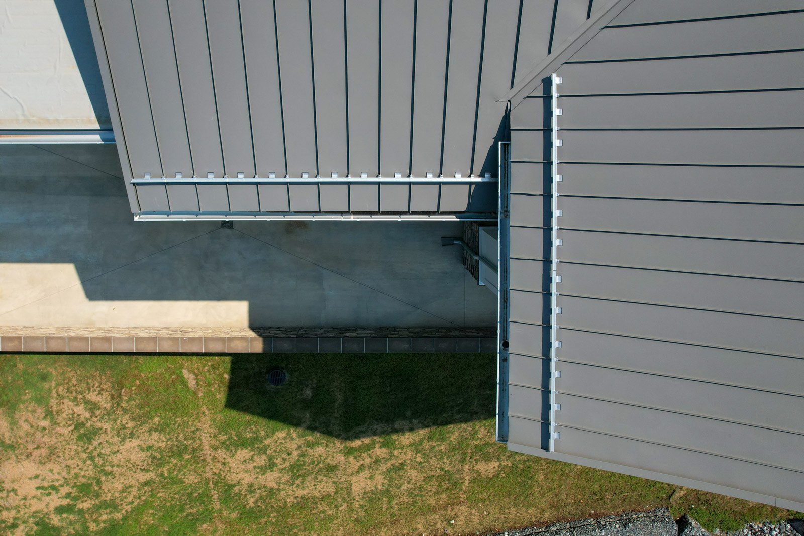 Close aerial view of the standing-seam metal roof, snow-retention system, gutters, and roof transitions.