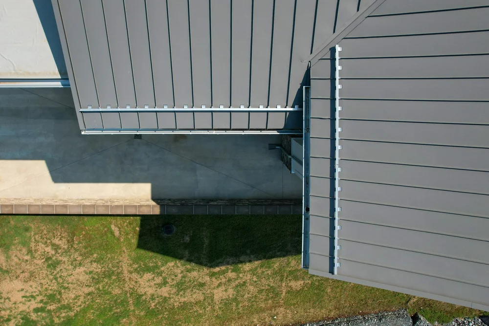 Close aerial view of the standing-seam metal roof, snow-retention system, gutters, and roof transitions.