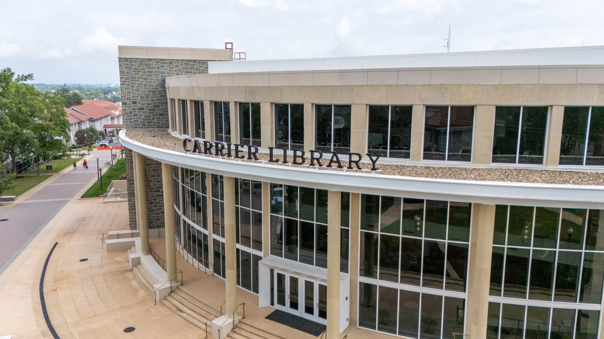 Close-up aerial view of the curved clay tile roofline and white trim above the Carrier Library entrance, with the "Carrier Library" signage visible on the building facade.