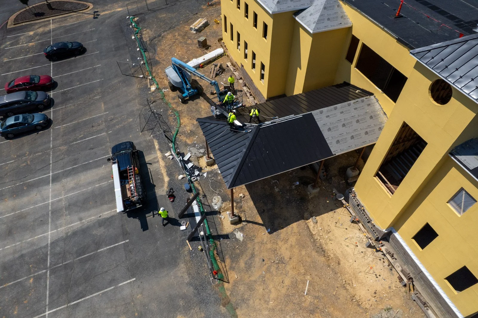 Aerial view of workers installing black metal roofing on the entrance canopy at Covenant Presbyterian Church in Harrisonburg, VA.