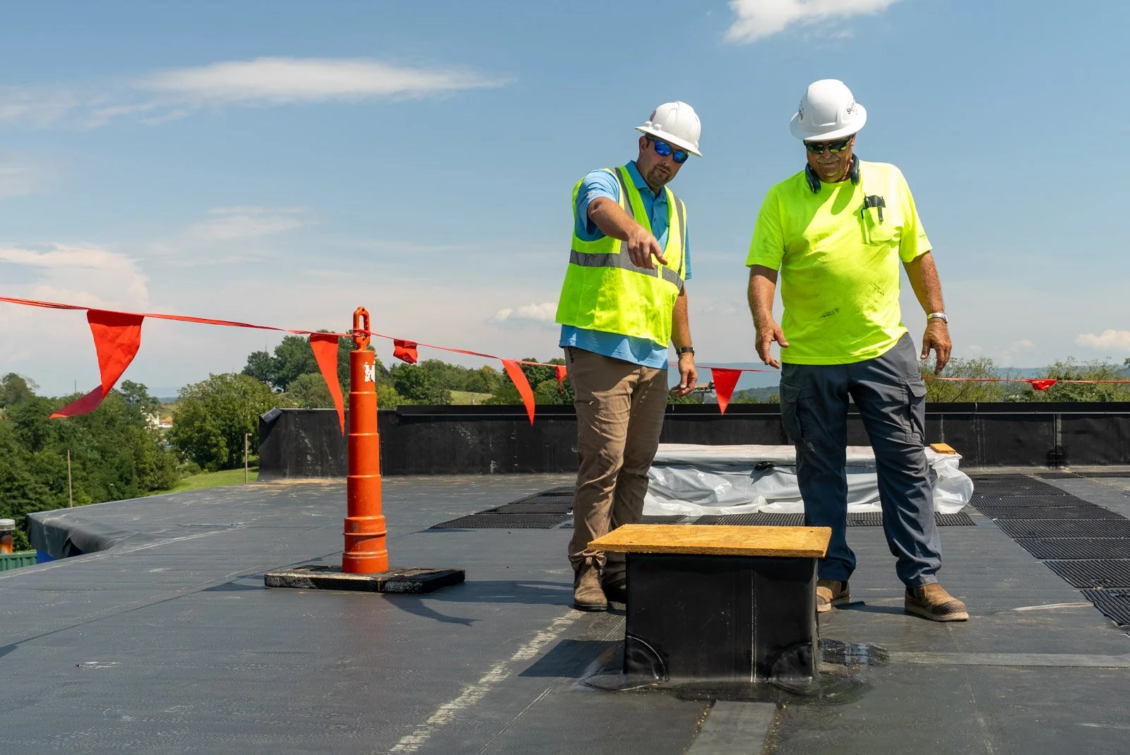 Two workers examine the EPDM roof near a covered rooftop opening at Covenant Presbyterian Church in Harrisonburg, VA.