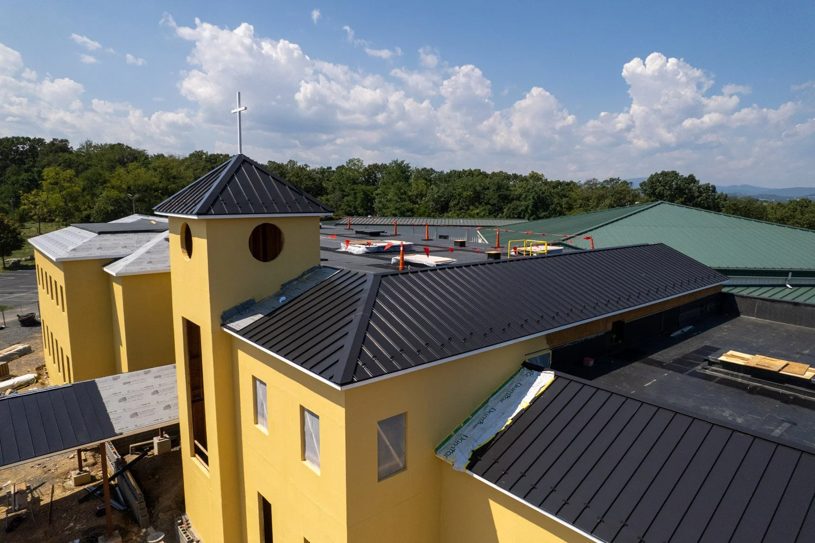 Elevated view of Covenant Presbyterian Church in Harrisonburg, VA, showing EPDM roofing progress and black metal roof sections.