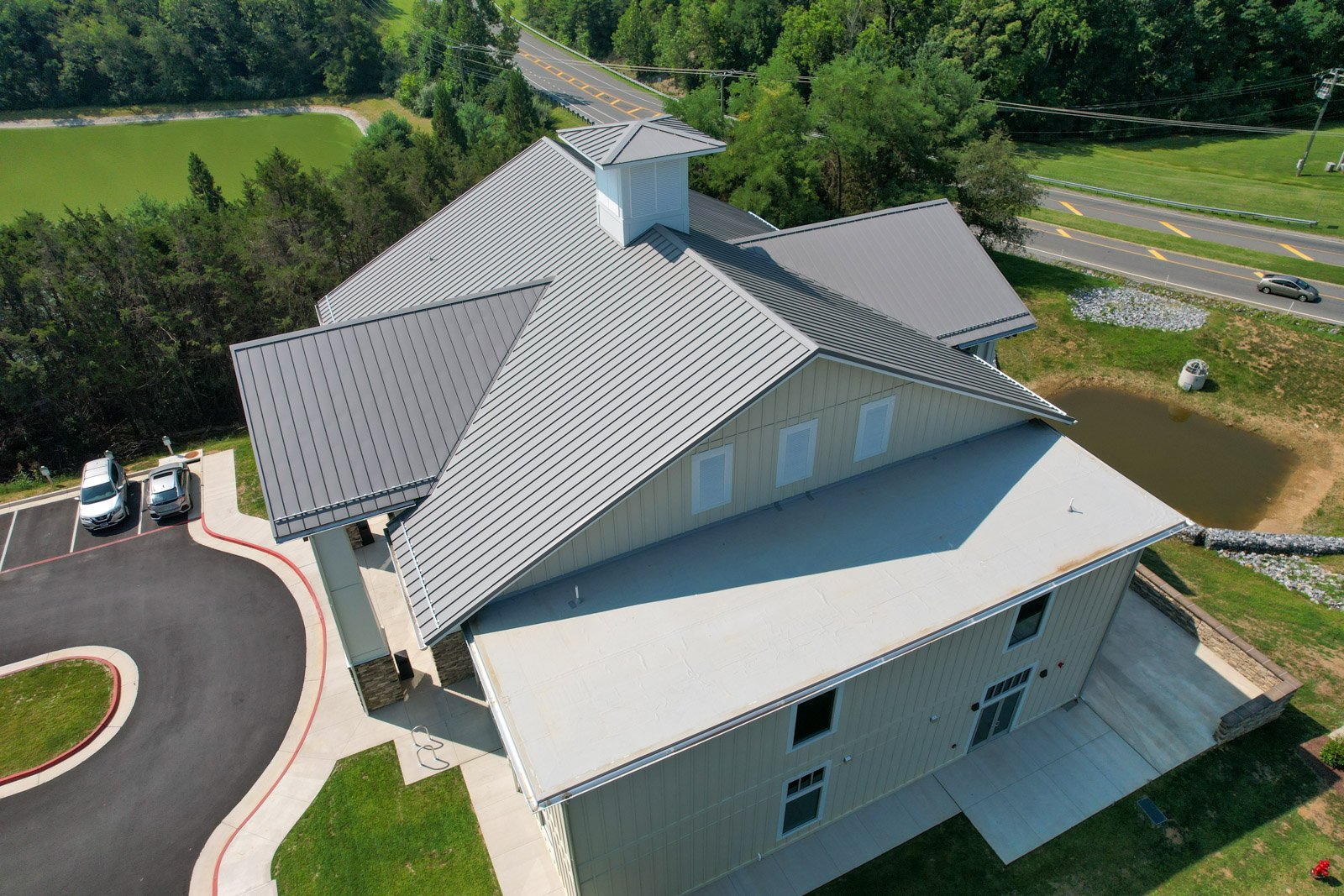 Aerial view showing the building’s standing-seam metal roof and low-slope TPO roofing system.