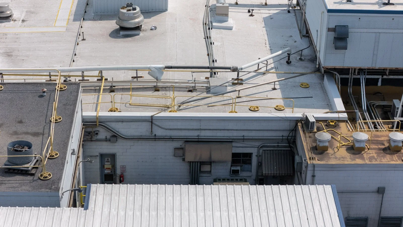 Close aerial view of the Farmer Focus industrial roof with rooftop equipment, piping, and yellow safety railings.