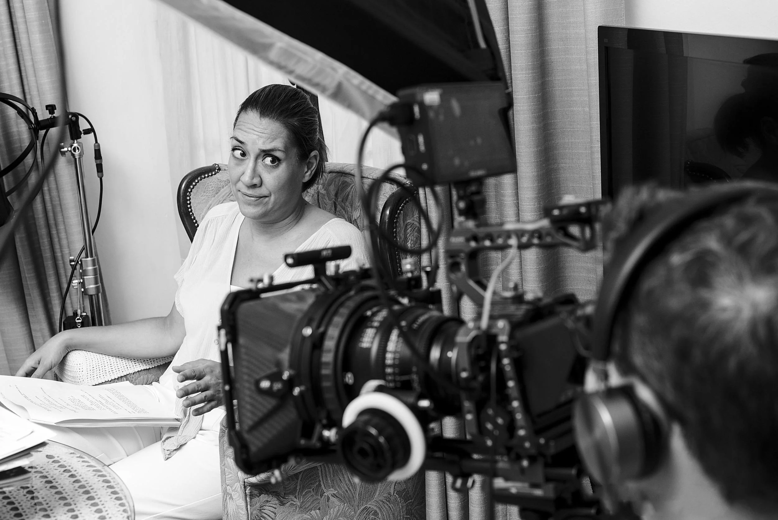 Actress sitting with film camera and lights in foreground during an interview.