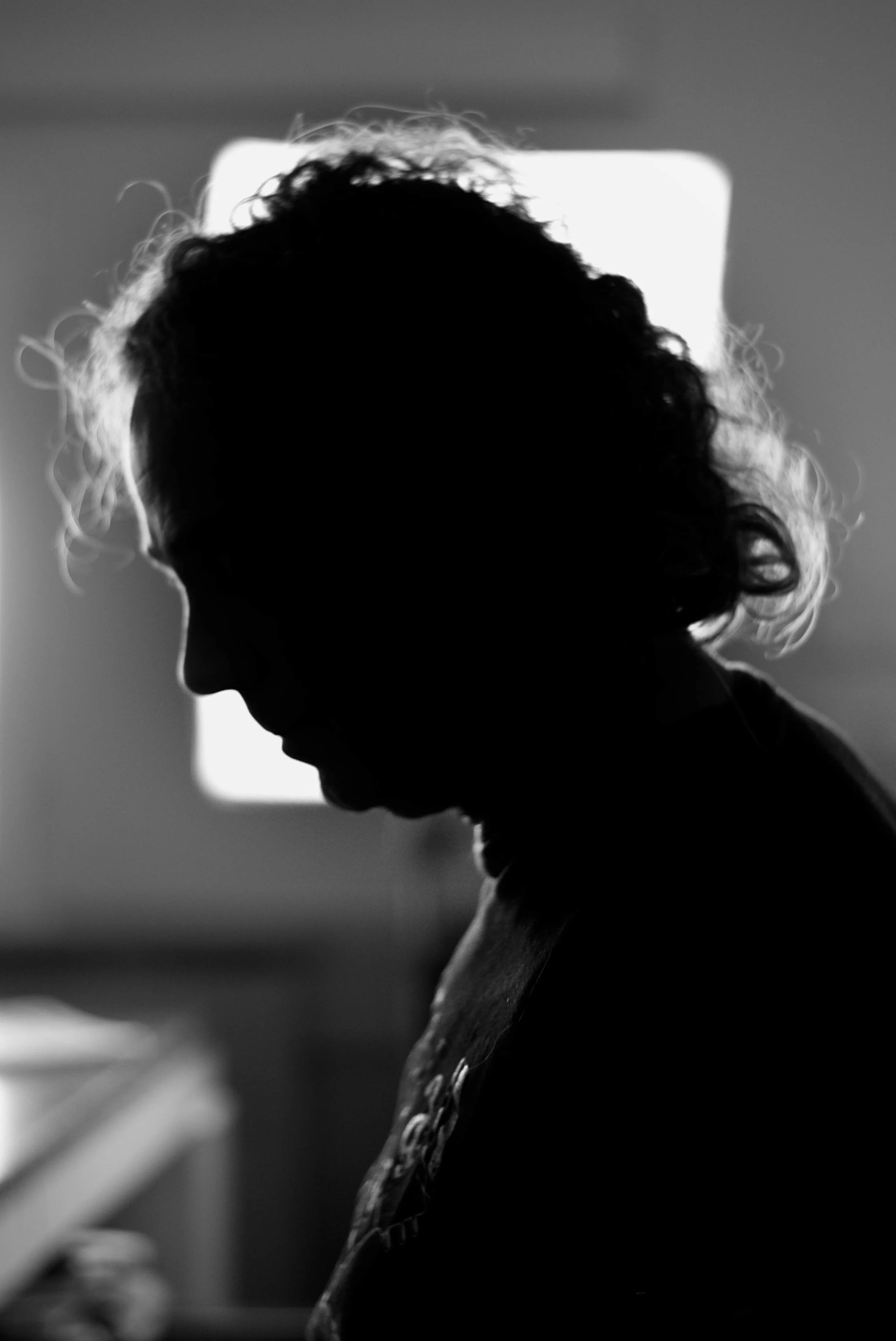 Silhouette of sound engineer with curly hair backlit in a room.