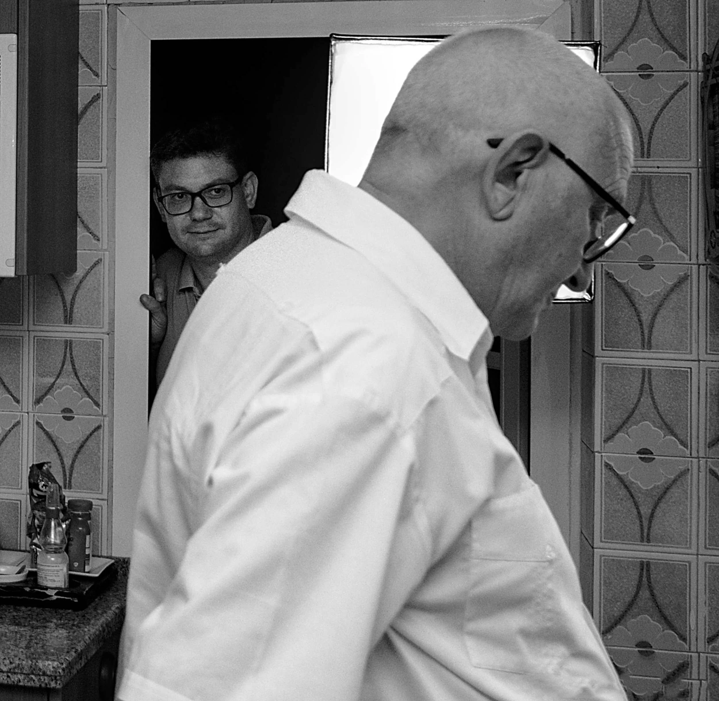 Director of photography watching an actor from a doorway on a kitchen set.