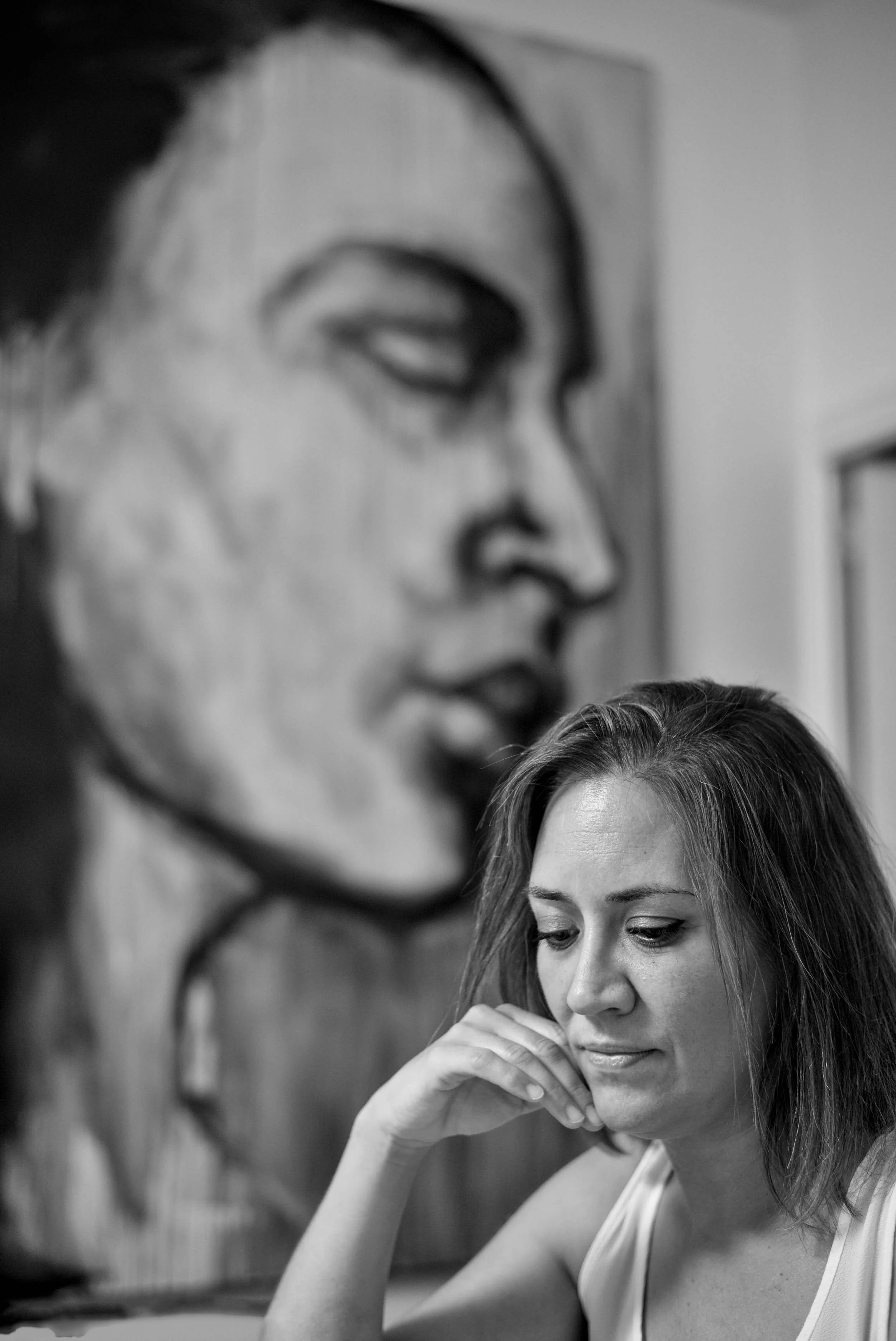 Director seated in front of a large painted face, thinking about the film script.