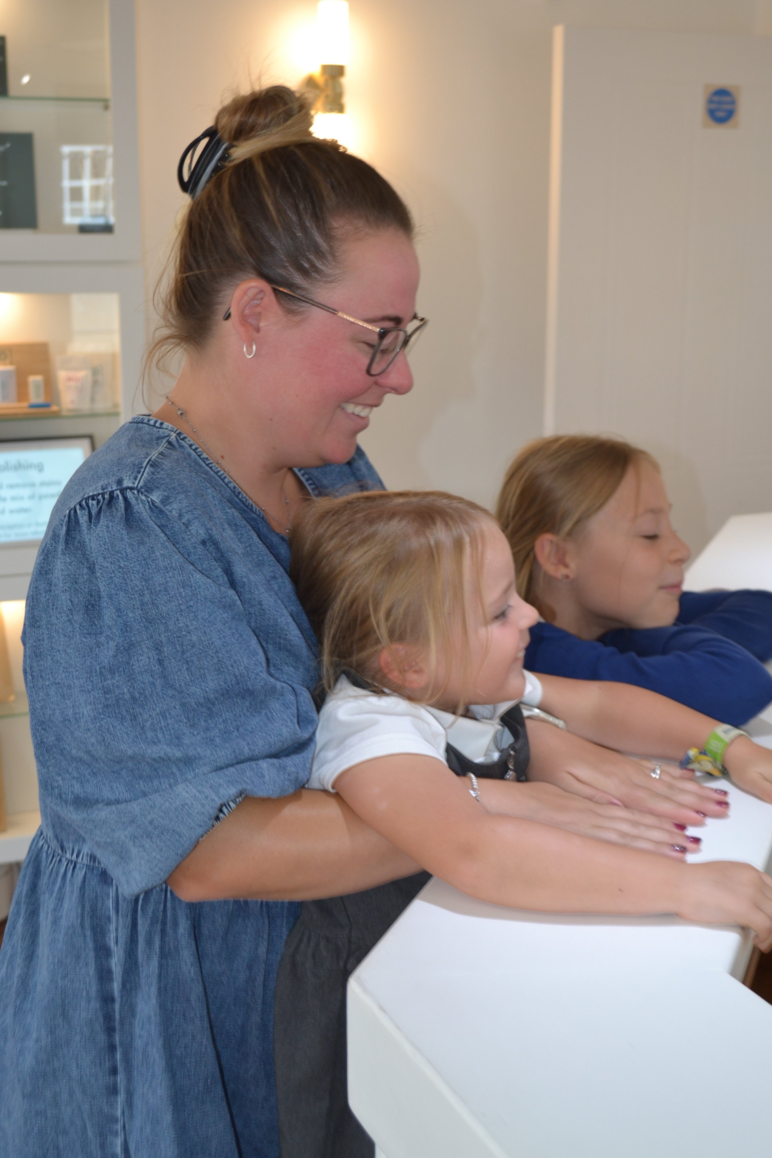 A mother and her two daughters smiling together at The Yorkshire Grey reception desk.