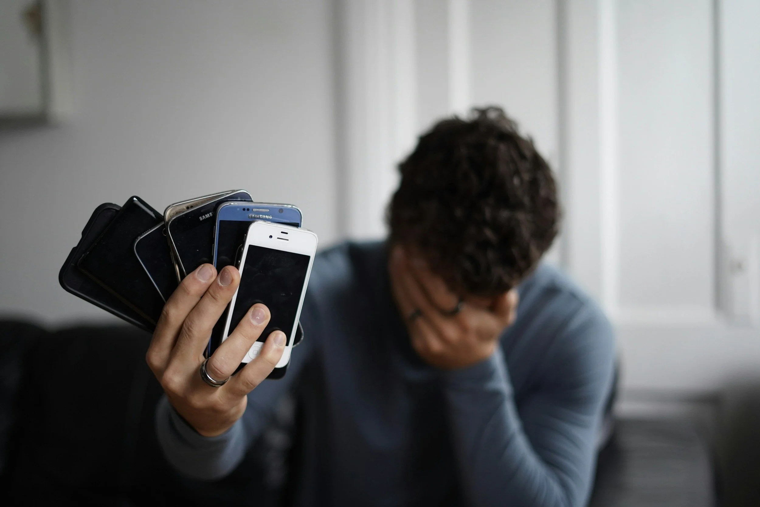 exhausted man holding phones
