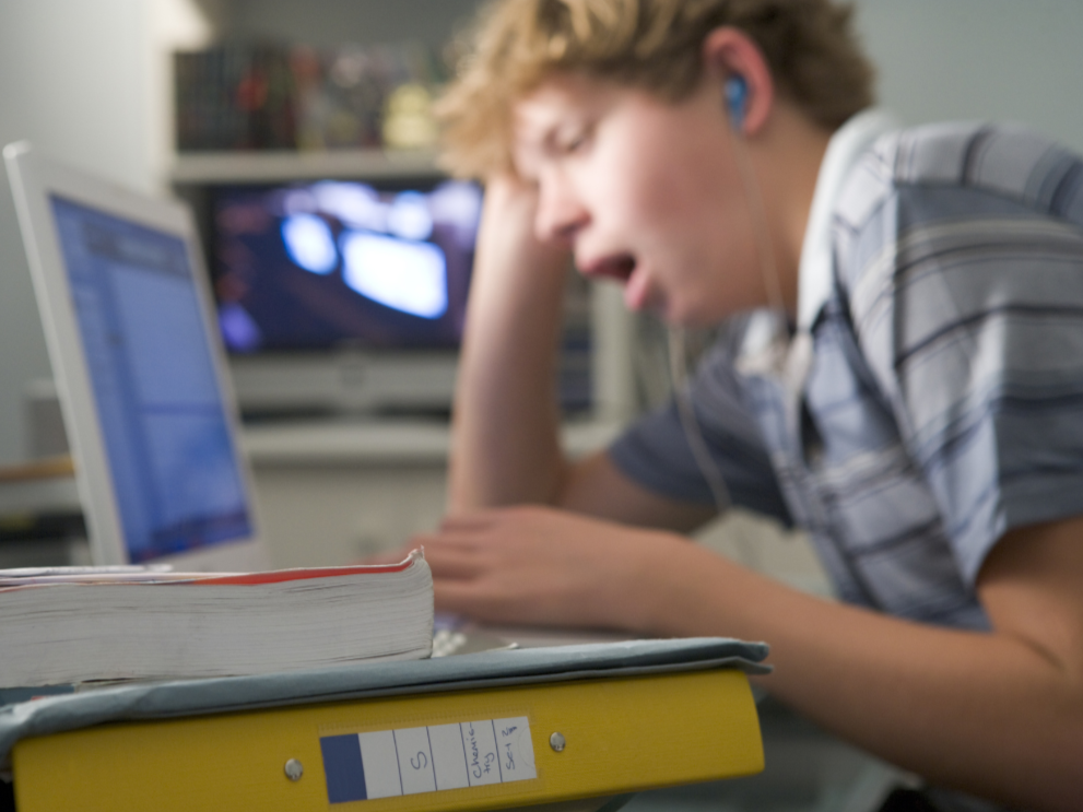 student yawning and looking at laptop