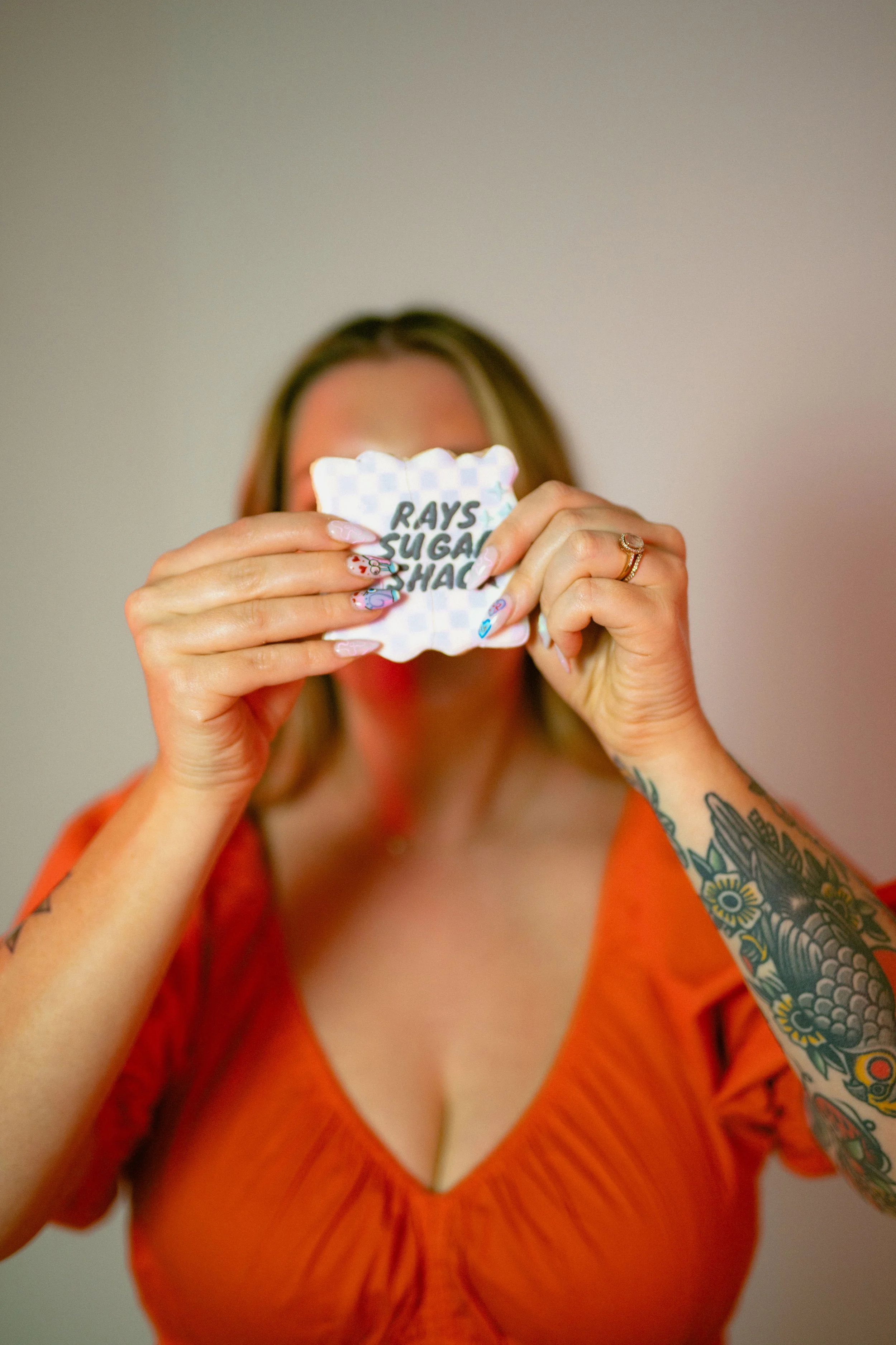 Southern California cookie decorator and home baker holding custom sugar cookie with playful expression during a colorful branding portrait photoshoot. Lifestyle marketing photography highlighting creative small business owner personality, captured b